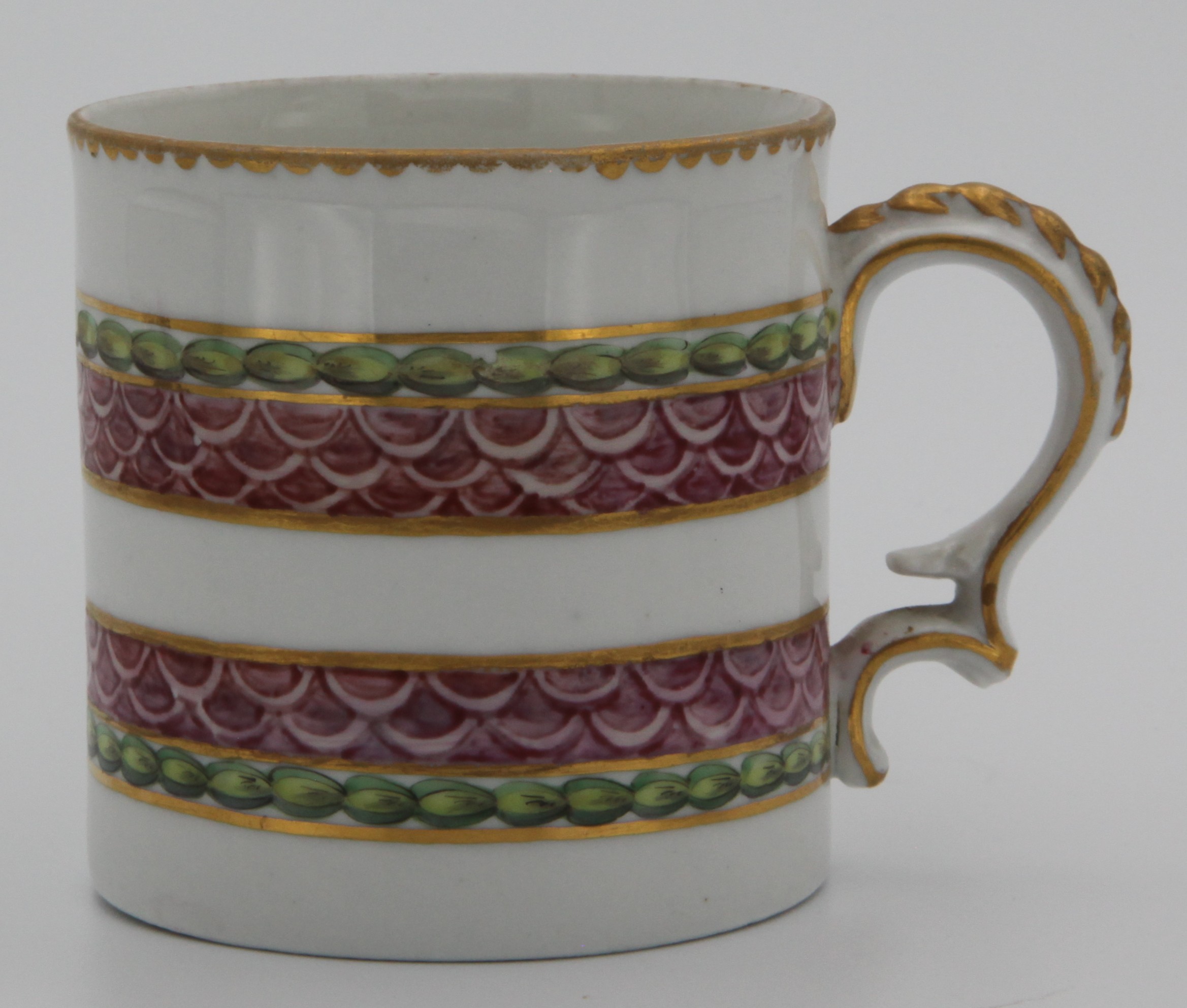A fine Bristol coffee can with harebell moulded scroll handle, painted in pink with scale bands, within green laurel borders, gilt dentil rims, circa 1775, blue painted X on cup, X4 on saucer. Condition: minor surface wear. See Albert Amor Limited, The Alfred Trapnell Collection, 1912, numbers 27 and 28 for similar examples