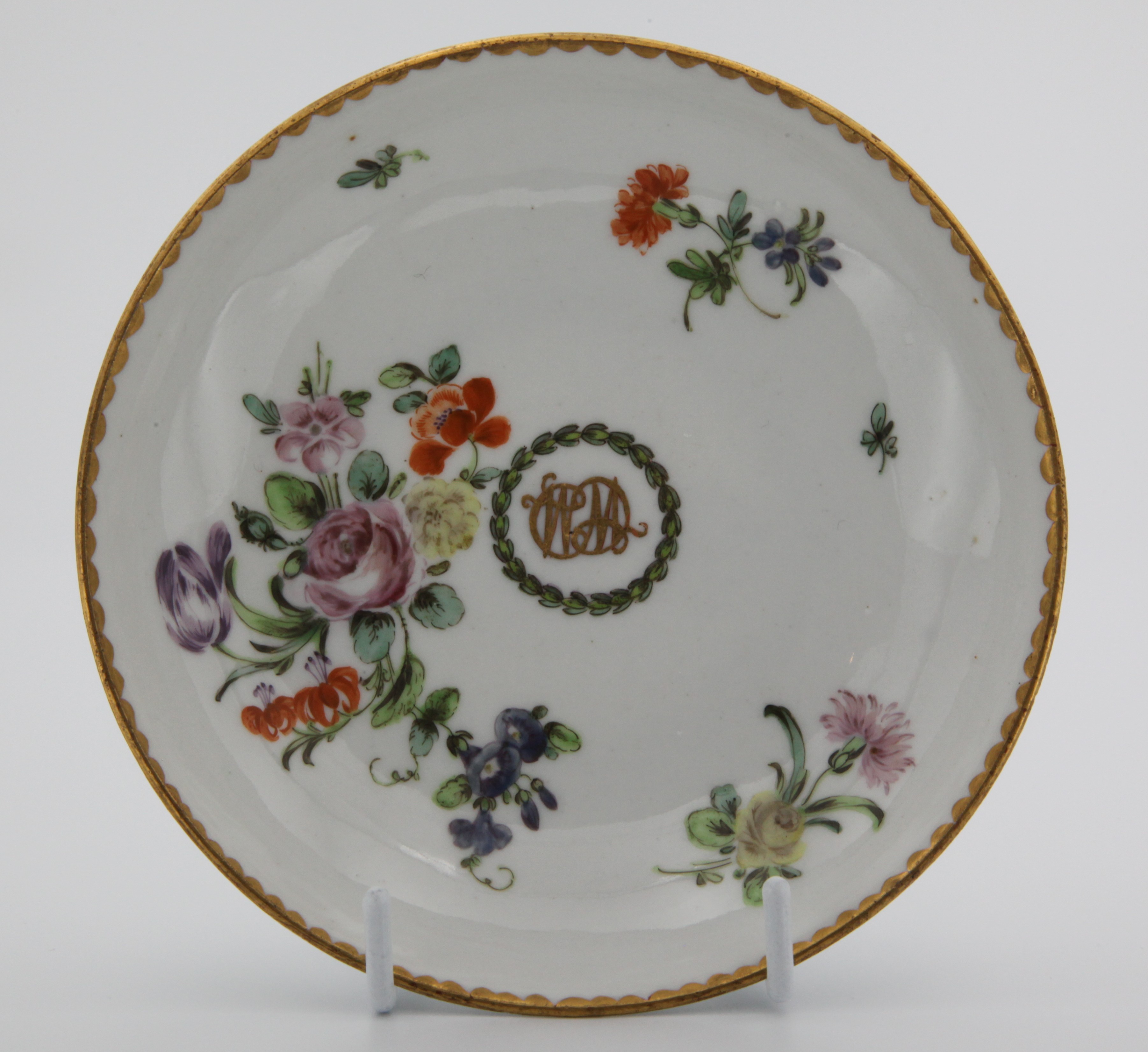 A rare Bristol tea saucer from the William Cowles Service, finely painted in coloured enamels with a bold spray of flowers and leaves, and scattered flowers, and with conjoined initials in gilt ‘WC’, within a laurel roundel, gilt dentil rims, circa 1774, no mark. From the service ordered by William Cowles of 33 Castle Green, Bristol, who was a Quaker and a friend of both Champion and Harford. The majority of this service is in the Lady Charlotte Schreiber Collection, in the Victoria and Albert Museum. See the Bristol Porcelain Bicentenary Exhibition, 1970, number 91c, for another tea bowl and saucer from this service.