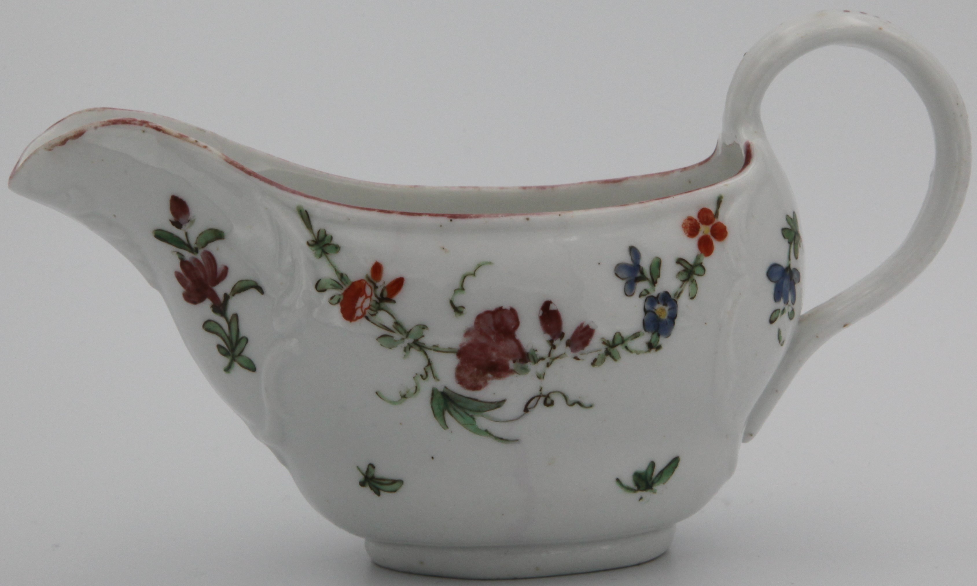 A rare Bristol ogee sauceboat, leafy scrolls, moulded in relief with painted with a floral swags and scattered sprigs, iron red rim, crossed swords, c.1770
