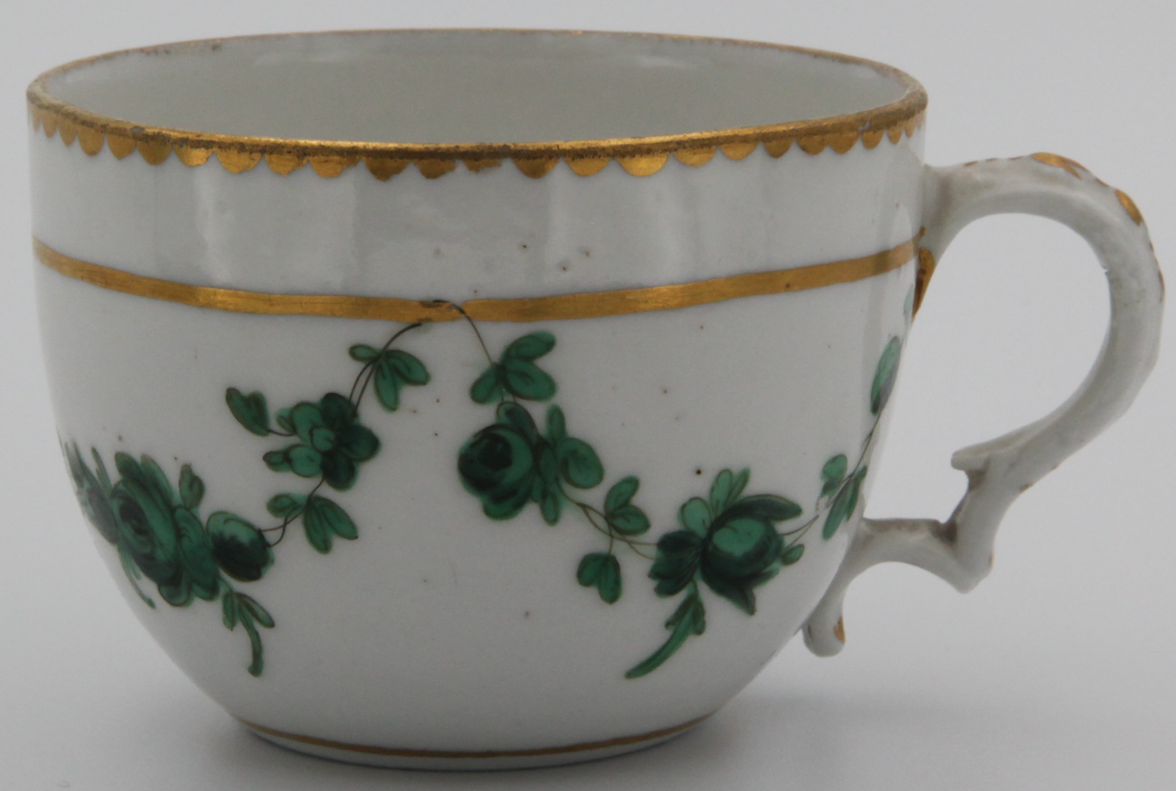 Bristol teacup with moulded handle decorated in gilt, finely painted  with green swags of flowers suspended from a thick gilt line, heavy gilt dentil rim. Mark: X1 (no dot)