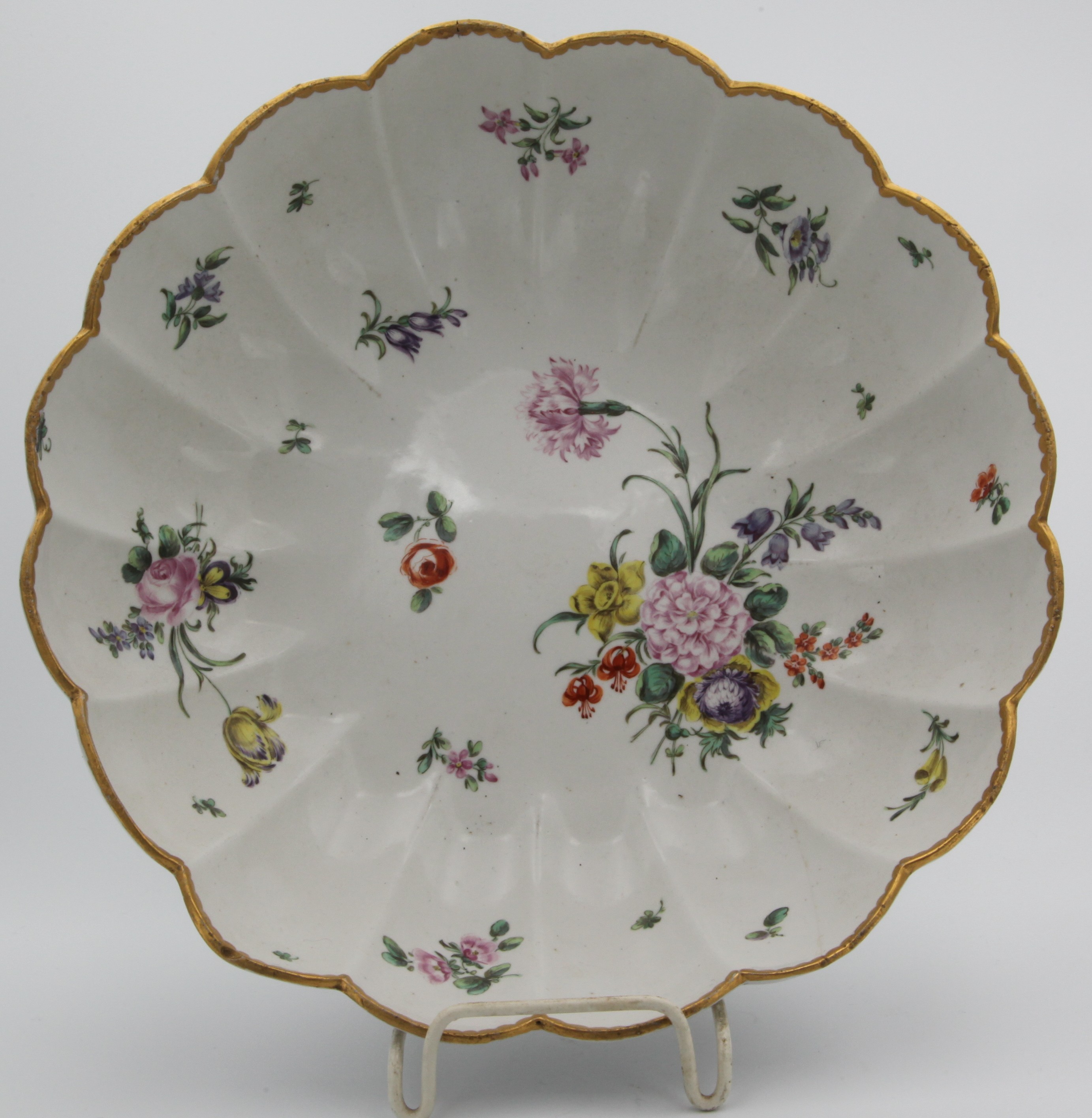 A large Bristol fluted junket dish, finely painted in coloured enamels with sprays of flowers and leaves, the lobed border with gilt dentil rim, blue painted X1. mark