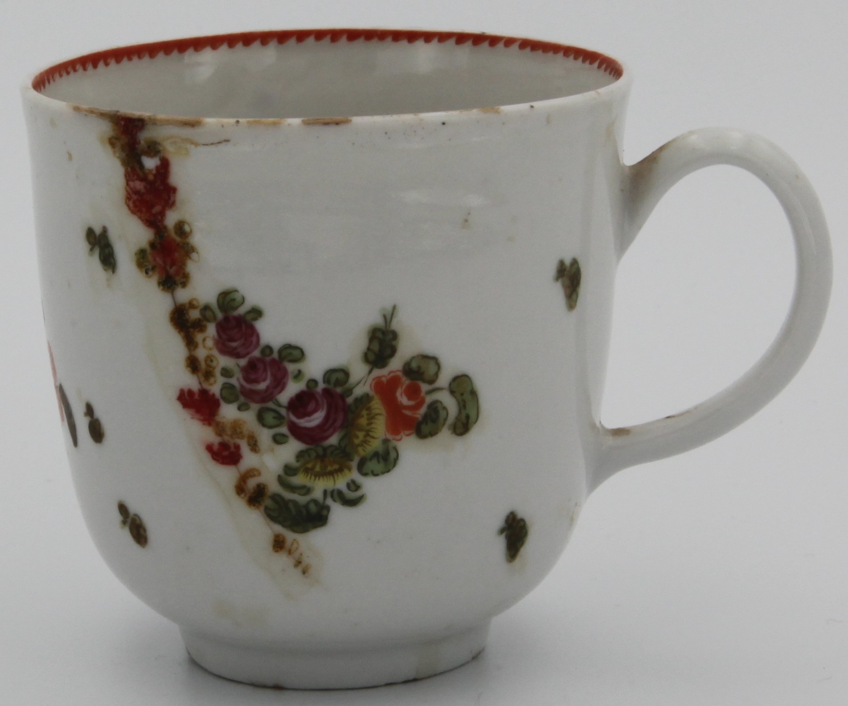 A Bristol coffee cup, with plain loop handle, decorated in untypical colours with floral sprays and scattered sprigs, the interior with dentil red rim, c.1770;