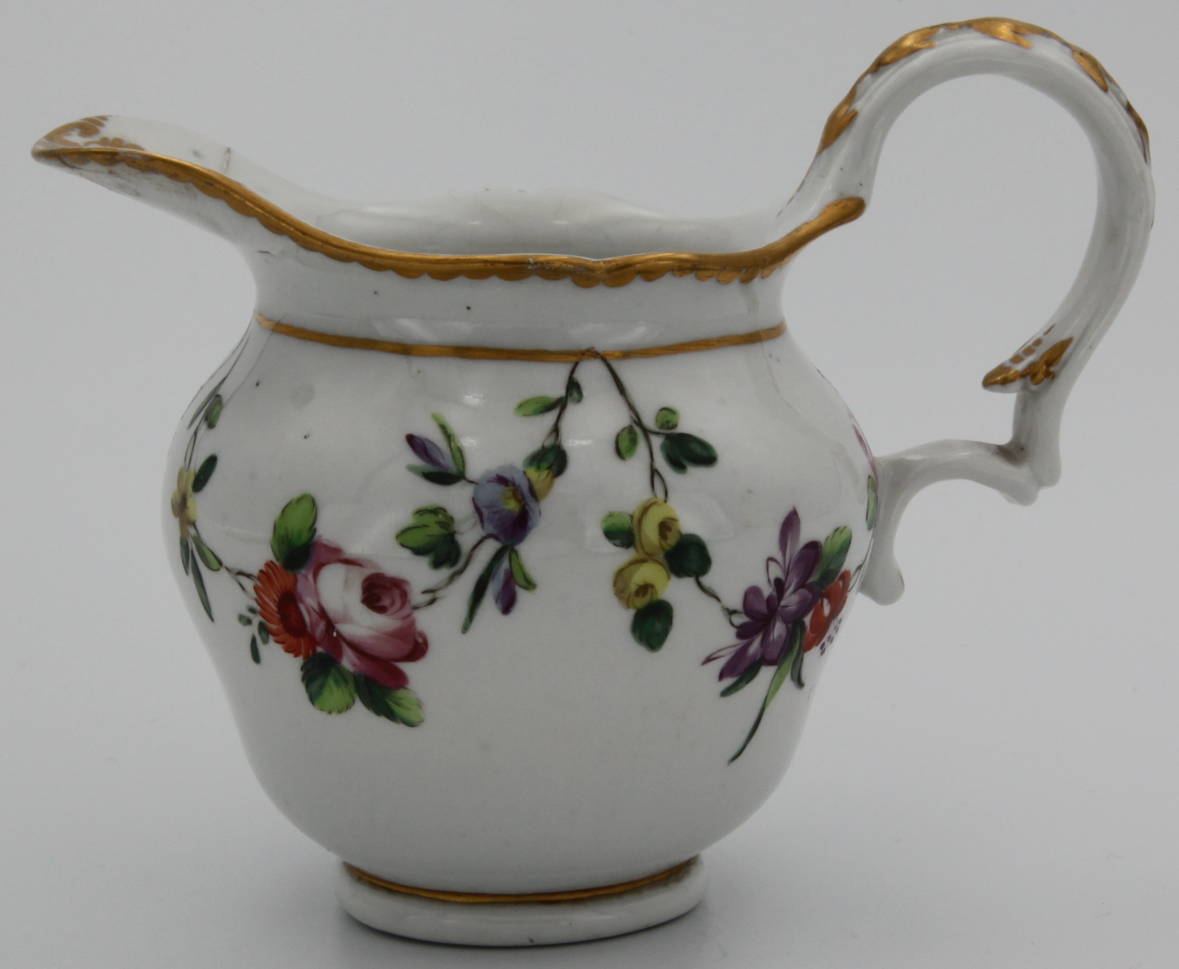 A ogee-shaped Bristol milk jug, with double scroll handle, painted in enamels with garlands of colourful flowers and leaves suspended from a gilt line, gilt dentil border,  blue X10 mark