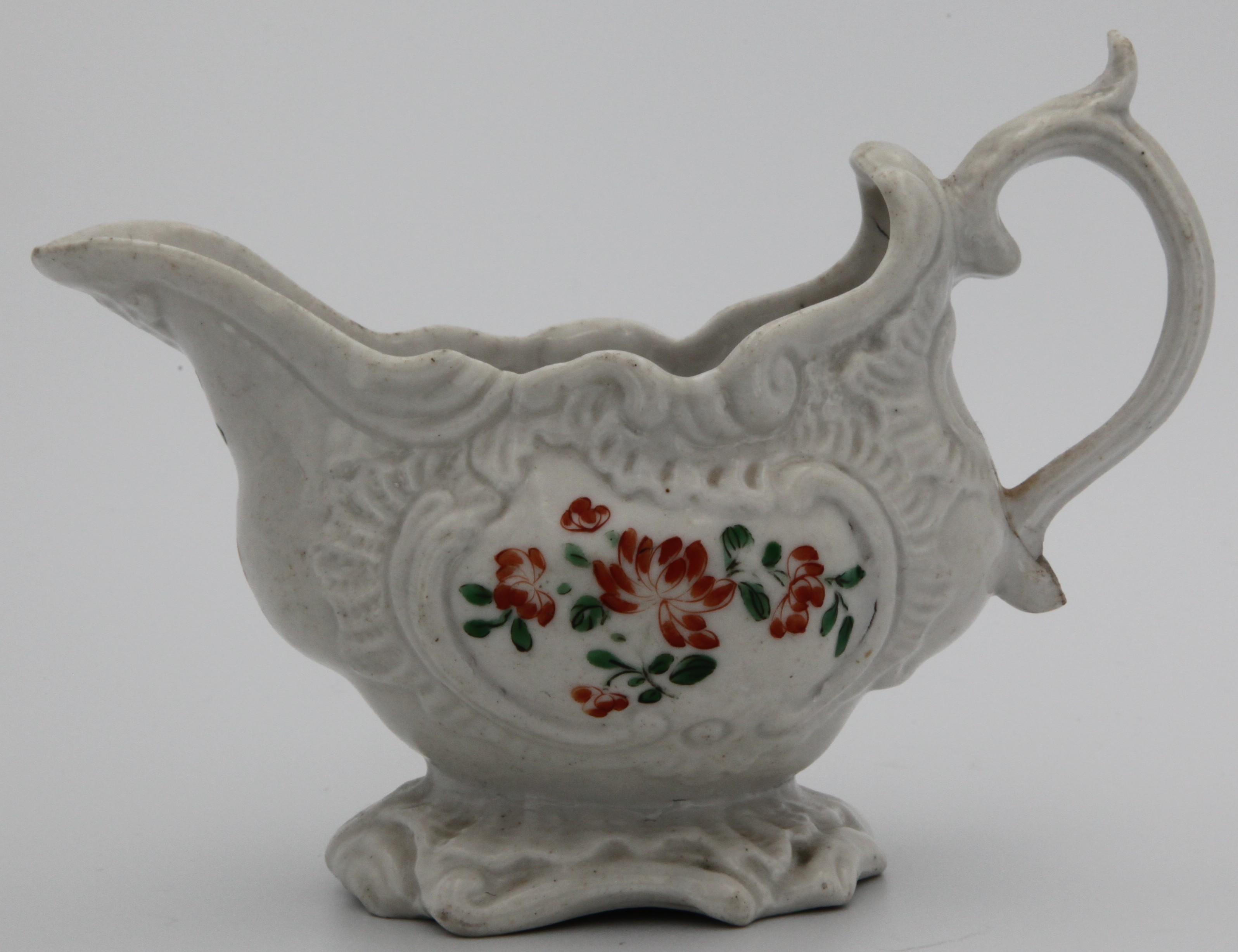 A Plymouth sauceboat with rococo scroll moulding painted with green and orange sprays, no mark 1768-70