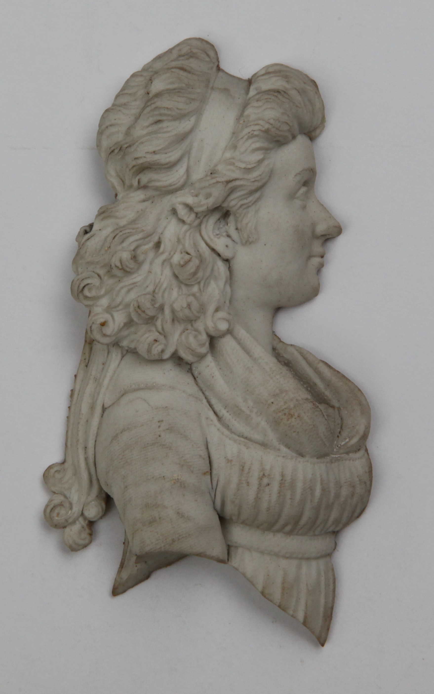 A biscuit plaque of a lady's head, part of a pair, mounted in a gilt frame with a note from Trapnell on the back reading "Bristol biscuit china. A pair v. similar sold at W. Edkins (of Bath) sale for @30 gns, about that. W. Edkins was a celebrated connoisseur & dealer". 63 and 403 from the Trapnell Catalogue