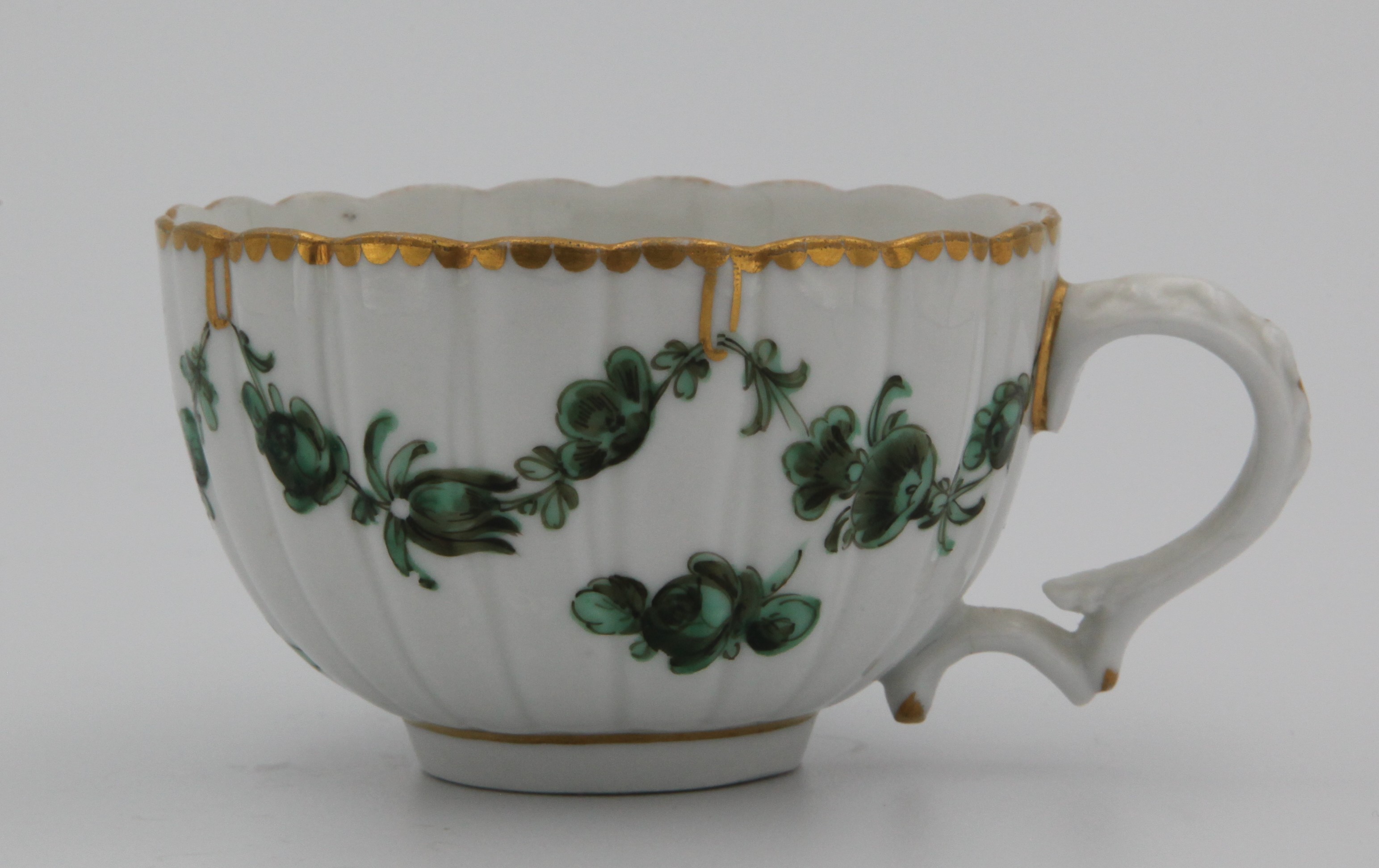 Afluted Bristol cup, painted with green and black monochrome garlands suspended from gilt loops hanging from a gilt dentil rim. Mark: blue X1.