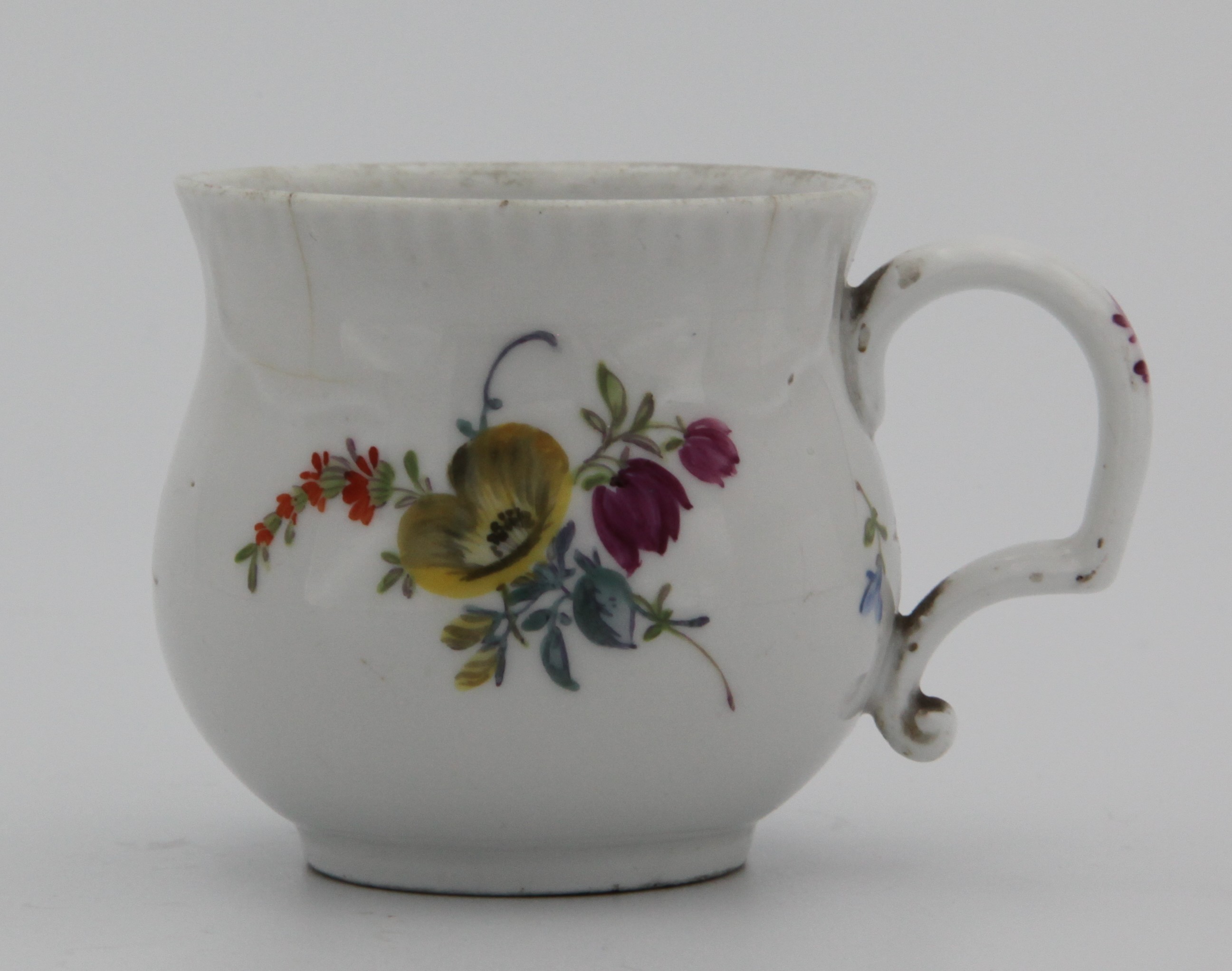 A small Bristol cup of baluster form with scroll handle, with unusual slight moulding to the rim, finely painted in enamels with coulourful sprays of flowers, blue crossed swords mark.