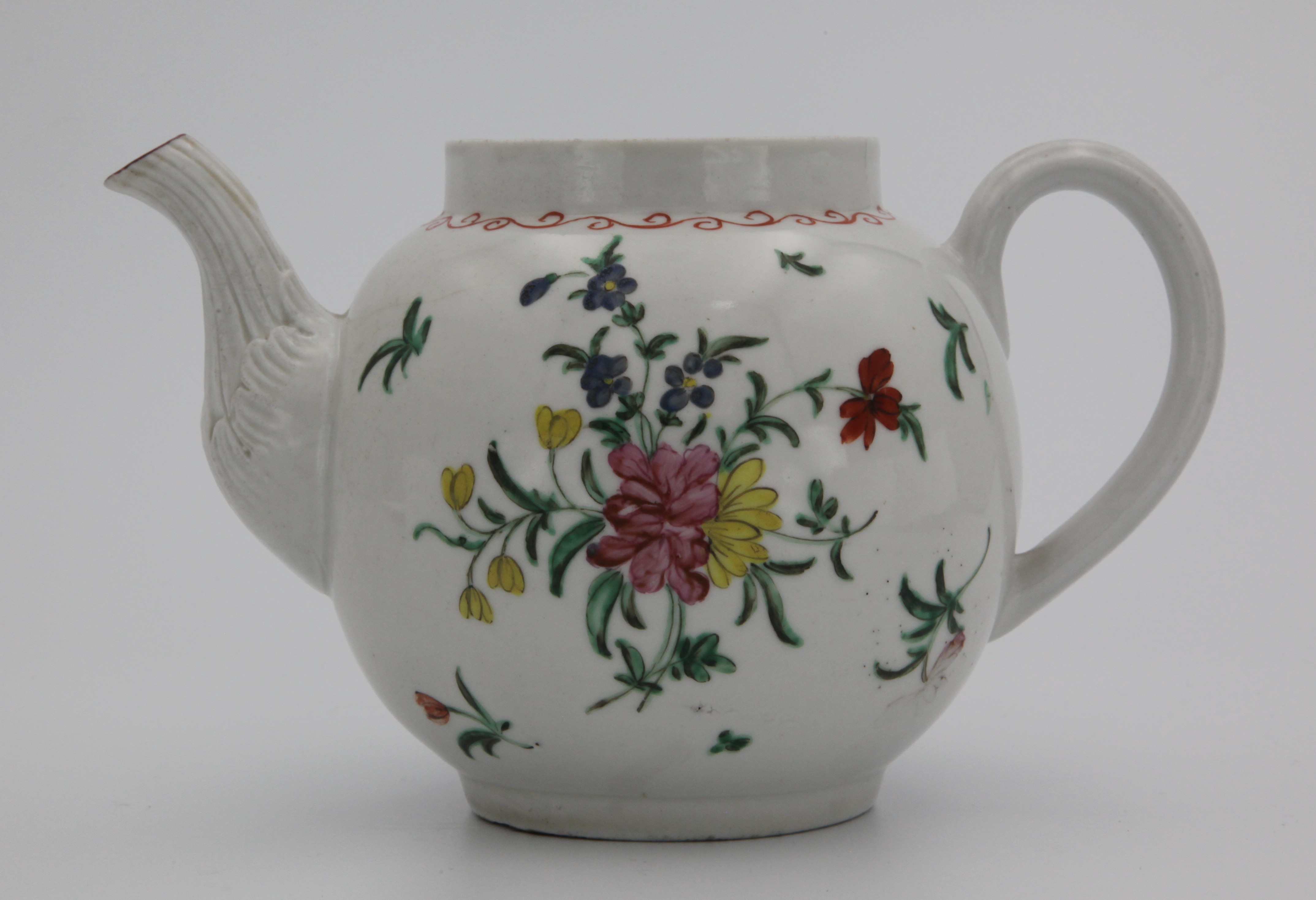 A Bristol teapot of rounded shape, with ridged loop handle and with moulded stiff leaves around spout, painted in enamels with a loose bouquet of colouful flowers and leaves, and scattered leaves and flowrs under a looping orange rim band. Fading grey X mark