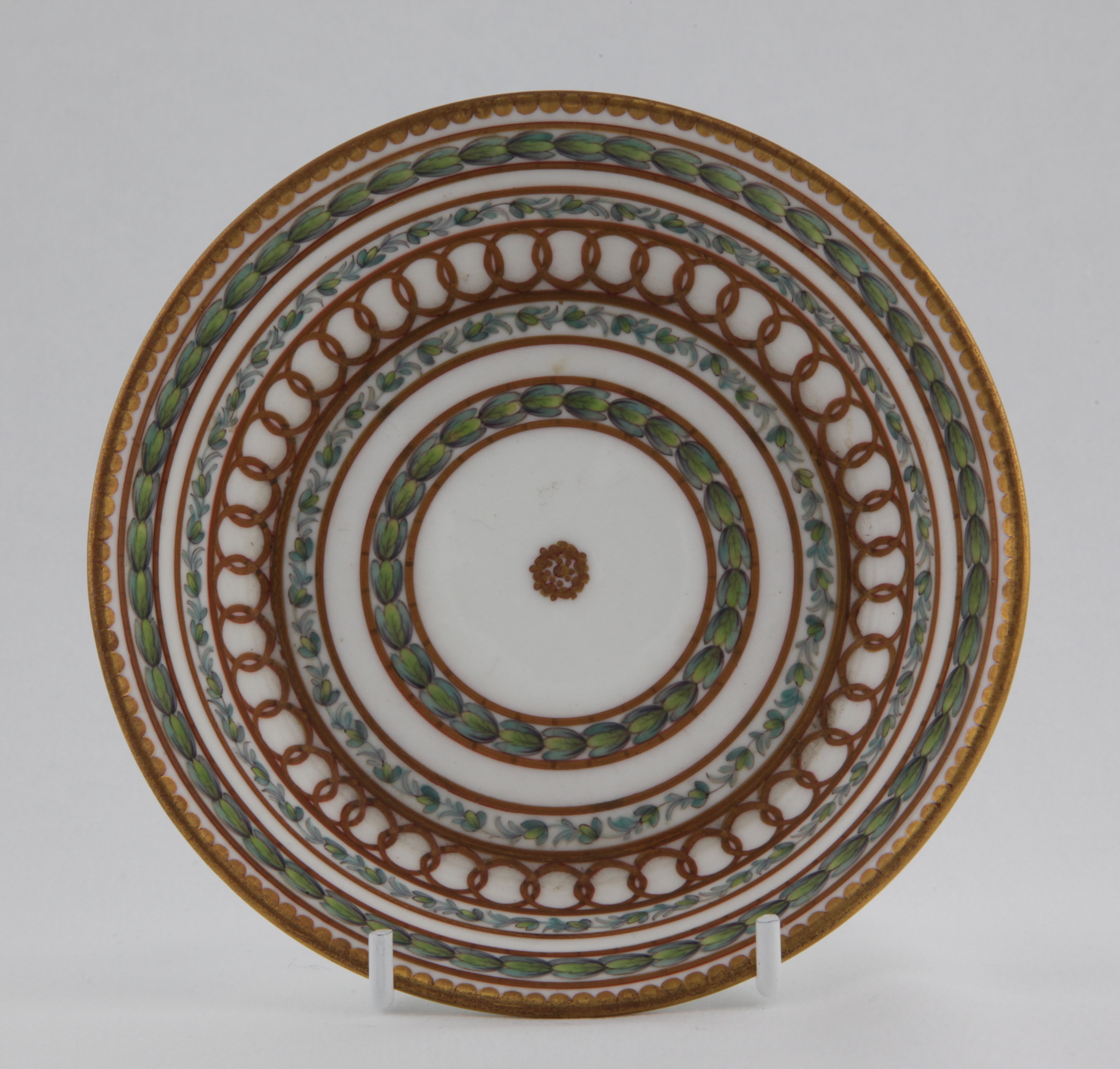 Saucer, from the Laurel bands service, decorated by 1, A Bristol cabinet cup saucer with bands of gilding and laurel leaves, painted in green and puce with bands of leaves, within gilt line and interlinked roundel bands, all around a central roundel and beneath gilt dentil rim — Plymouth & Bristol porcelain piece 1487