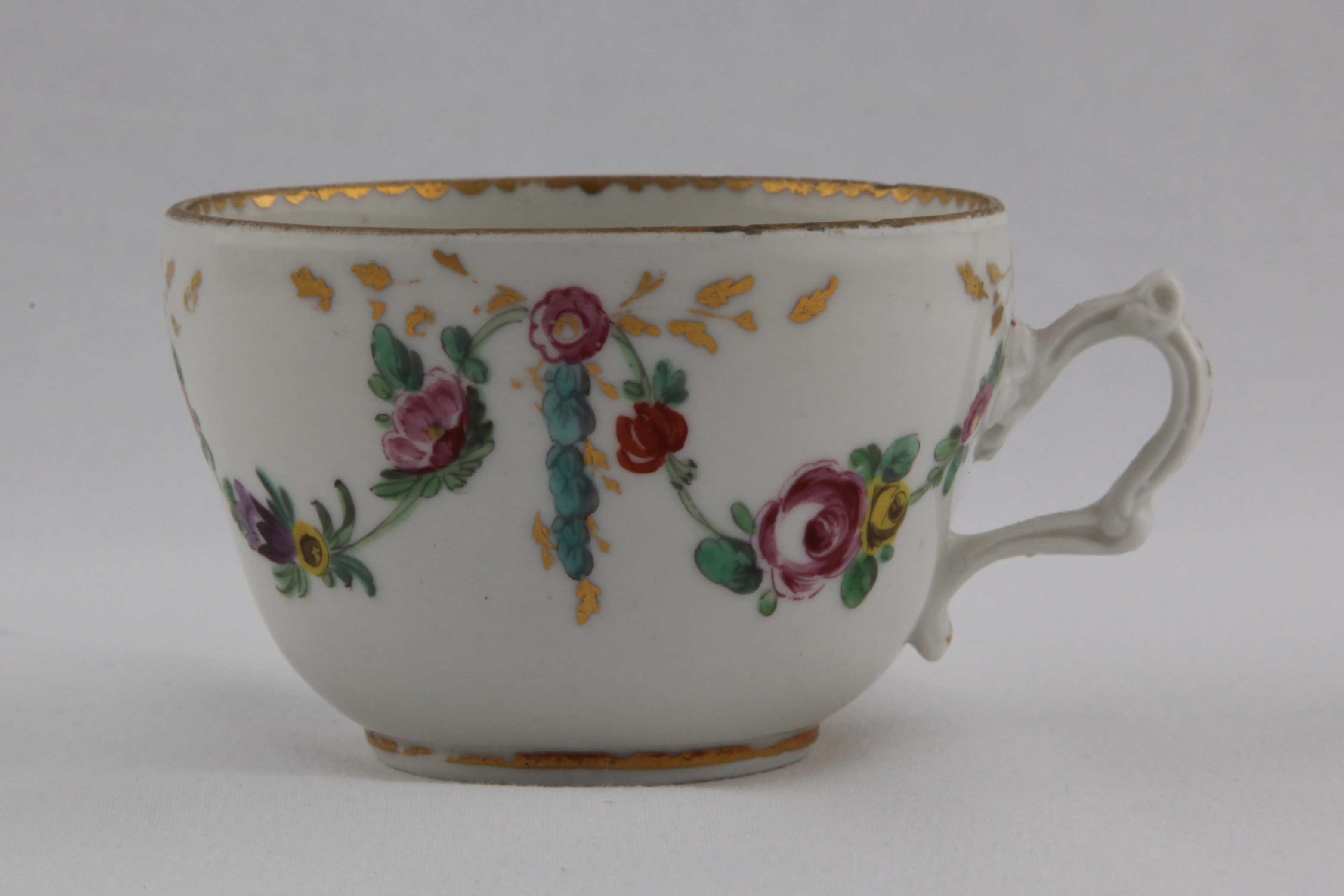 Cup, from the Pink rosettes gilt scrolls service, decorated by 1, A slightly ogee Bristol teacup with structured handle, painted in coloured enamels with swags of flowers and leaves, suspended from pink rosettes, from which issue gilt leaf scrolls and laurel, the interior painted with a pink rose, gilt dentil rim — Plymouth & Bristol porcelain piece 1490