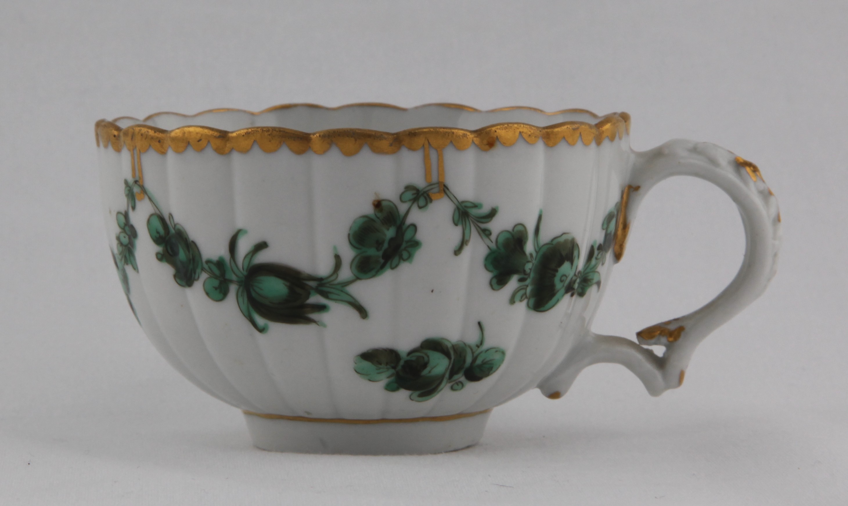 Cup, from the Horace Walpole service, decorated by 1, A fluted Bristol cup from the Horace Walpole service, with harebell moulded scroll handle, painted with green and black monochrome garlands suspended from gilt loops hanging from a gilt dentil rim — Plymouth & Bristol porcelain piece 1492