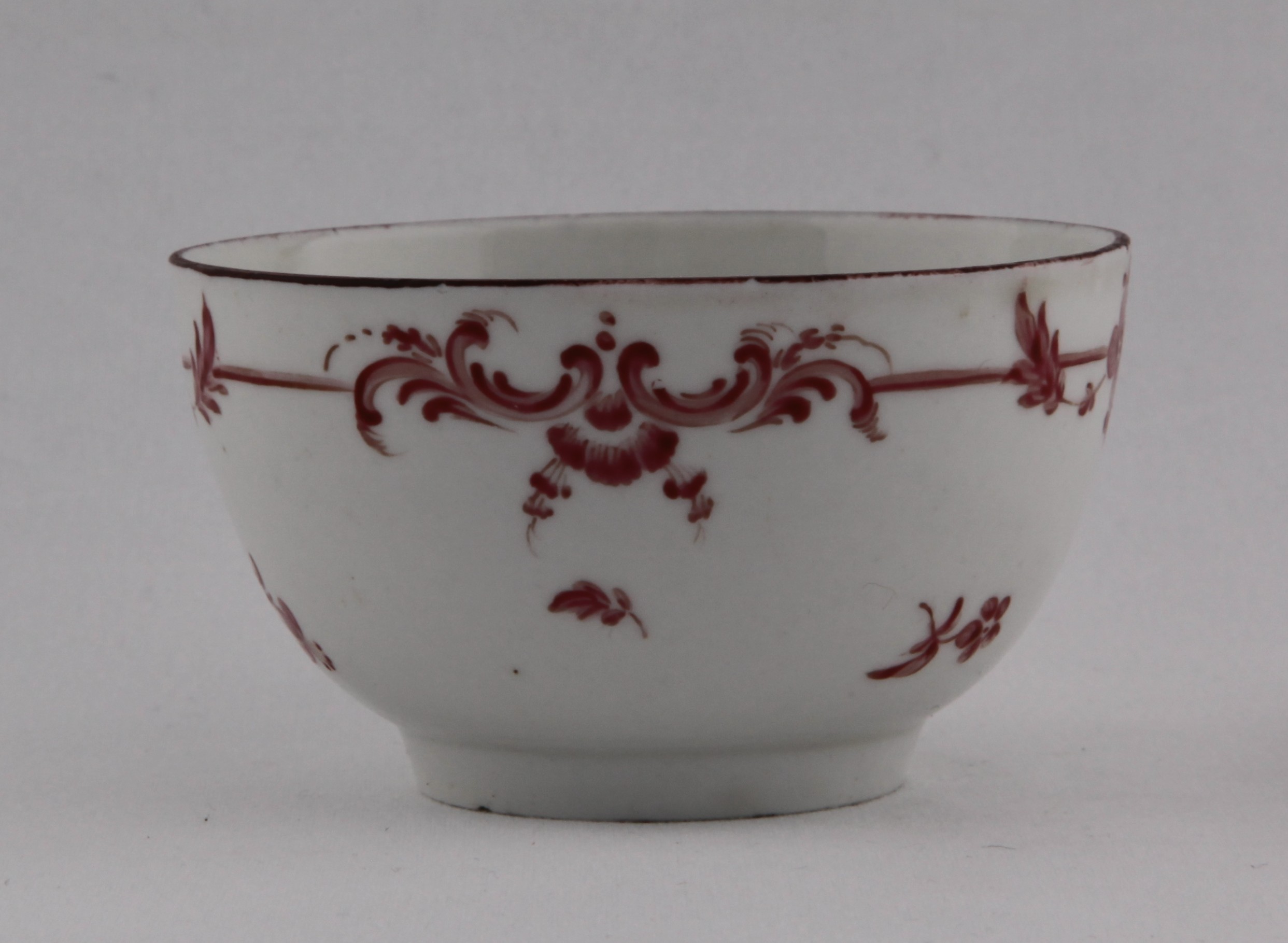 Tea bowl, from the Puce monochrome service, decorated by No mark, A Bristol tea bowl, of rounded shape, painted with monochrome puce scroll band with scattered flowers under an iron red rim line — Plymouth & Bristol porcelain piece 1499