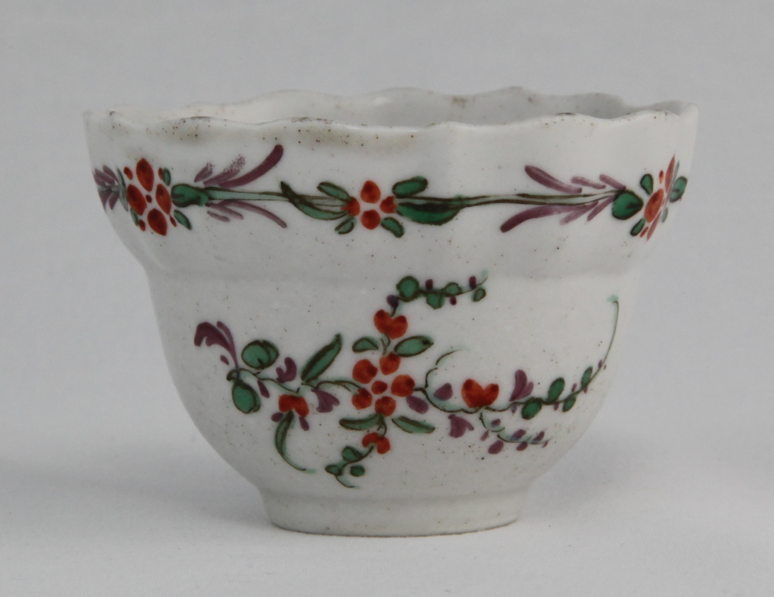 An extremely rare Plymouth ogee-form teabowl unusually polychrome painted with simple green, orange and puce floral sprays under a similarly coloured band.
