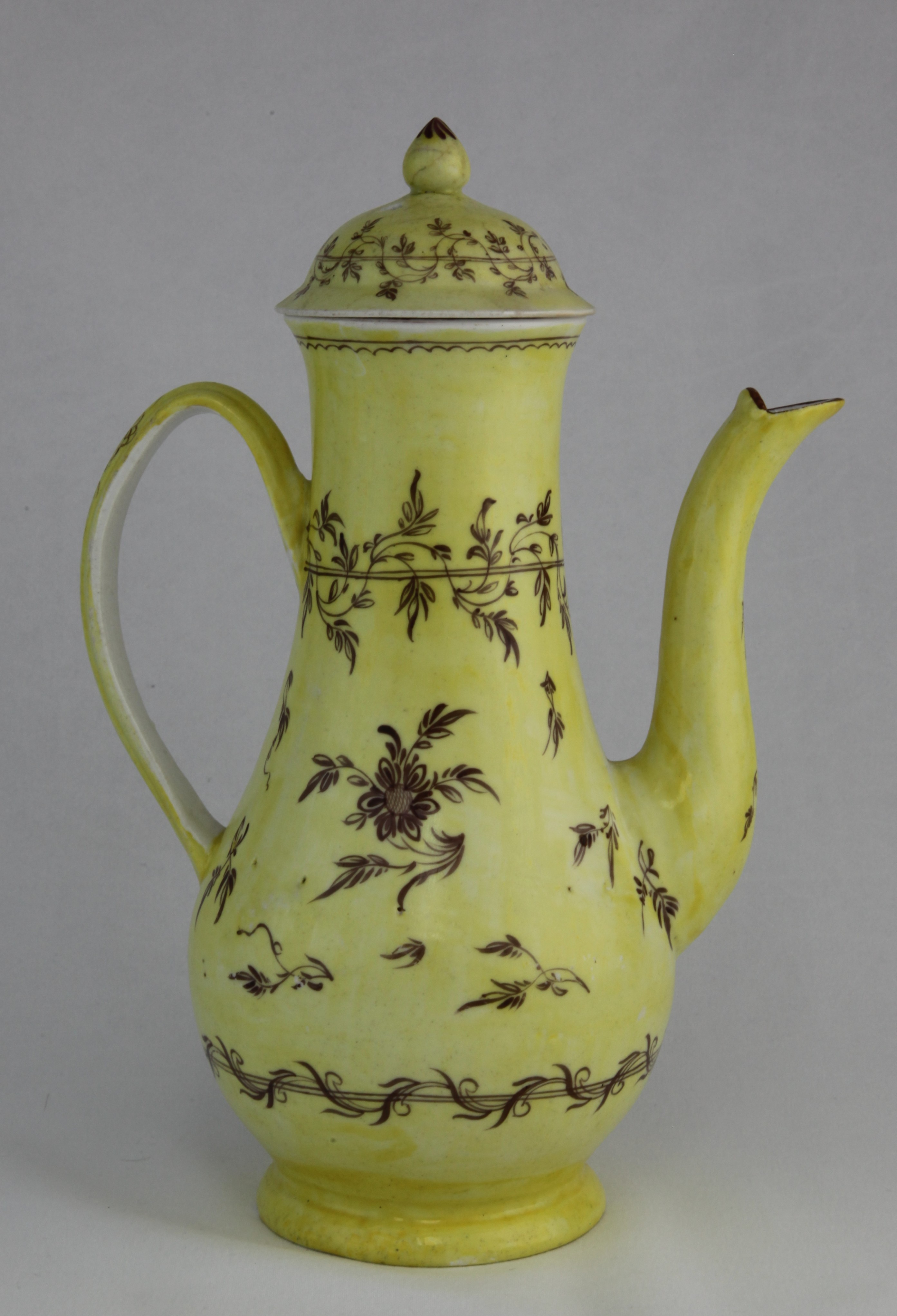 An extremely rare Plymouth yellow ground slender baluster shaped coffee pot and domed cover, with notched loop handle and pointed knop, painted in purple with flowers and leaves, within leaf scroll and ribbon borders, circa 1770, no mark