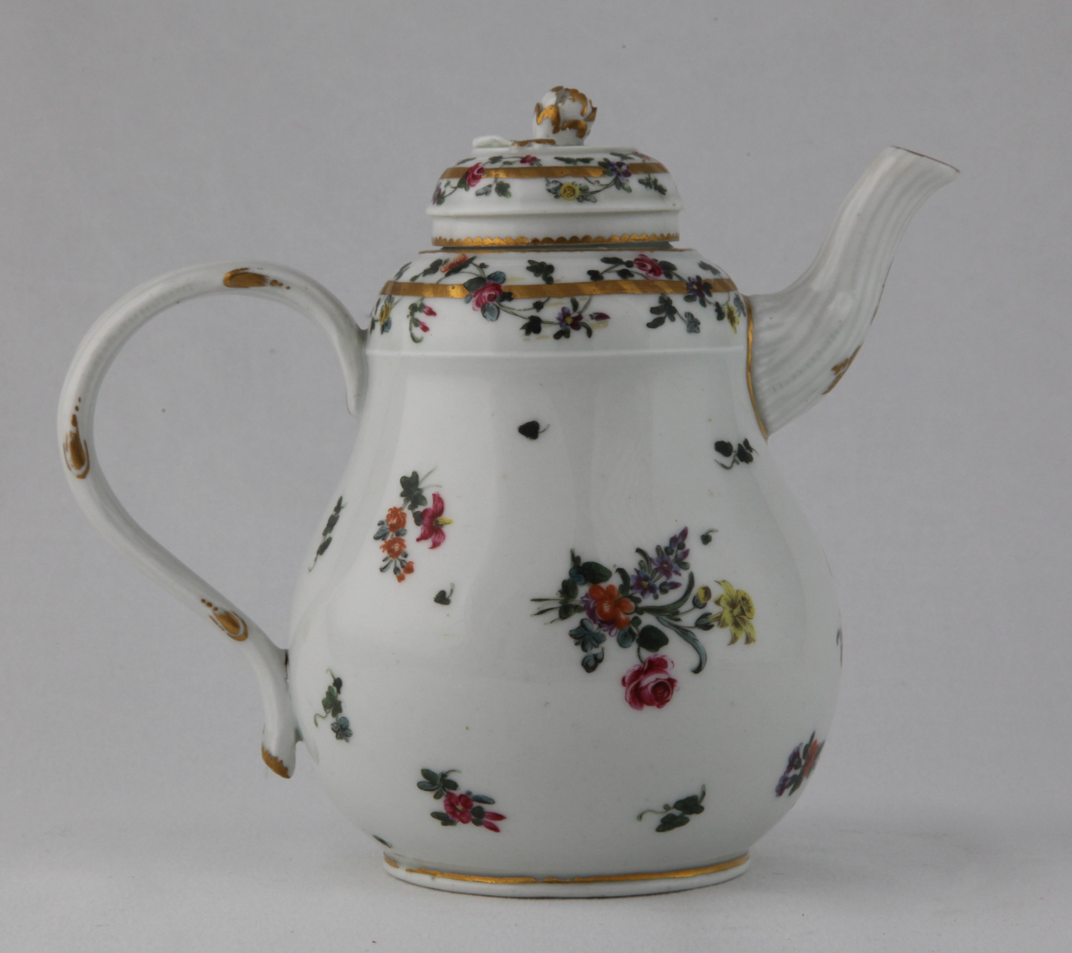An unusual Champion's Bristol teapot and cover, circa 1775, of distinctive pear shape with a crabstock handle and spout, painted with colourful sprays and sprigs of flowers, the shoulder and small domed cover with floral garlands entwined around gilt bands, with gilt dentil rims, the cover with a flower finial picked out in gilding