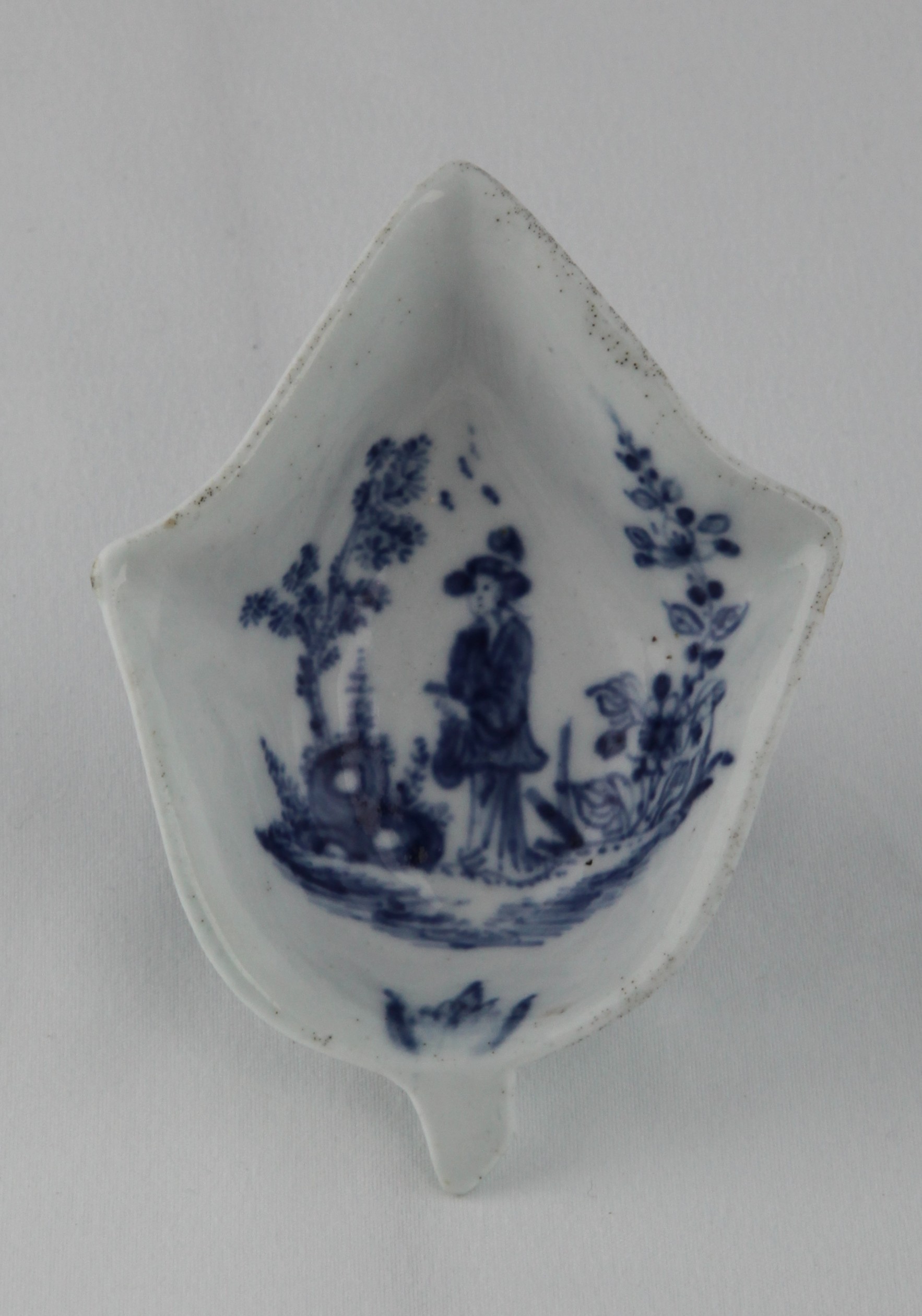 A Lund's Bristol pickle dish, circa 1750-52 modelled as a pointed ivy leaf, the underside with lightly moulded veins, painted in soft blue with the 'Pointing Chinaman' pattern, a 'Long Eliza' figure standing beside flowering shrubs and a curious rock, 10.4cm long