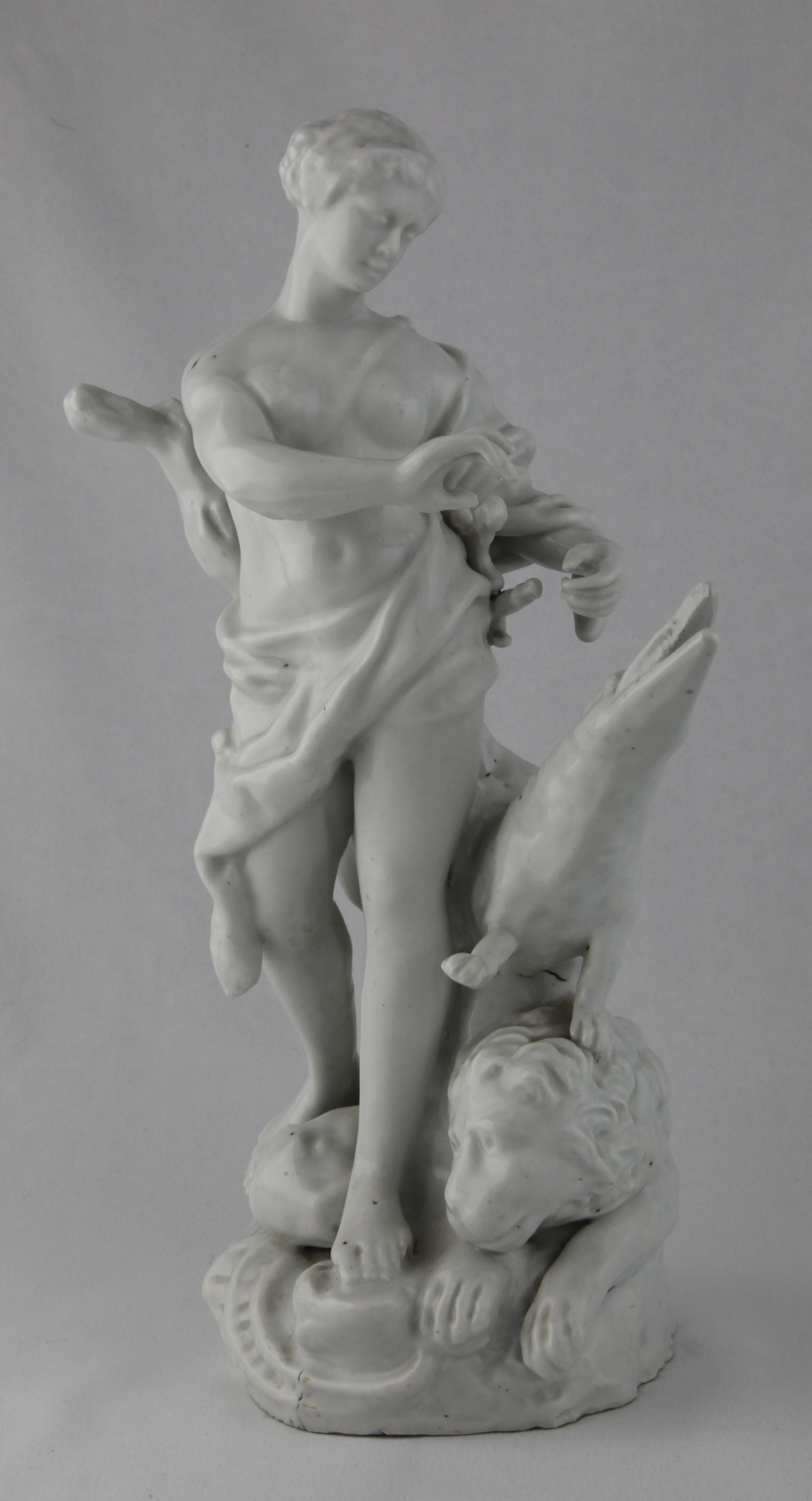 Africa, from a rare set of four Plymouth figures of the Continents, in the white, each represented by a standing young woman; America with feathered headdress and tunic, drawing an arrow from a quiver, a dog at her feet, Asia holding a censer, a camel at her side, Africa with a crocodile and a lion at her feet, and Europe holding a book and an artist’s palette, a horse, cannon and cuirass at her feet, each on scroll moulded mound base, circa 1768-70, no marks