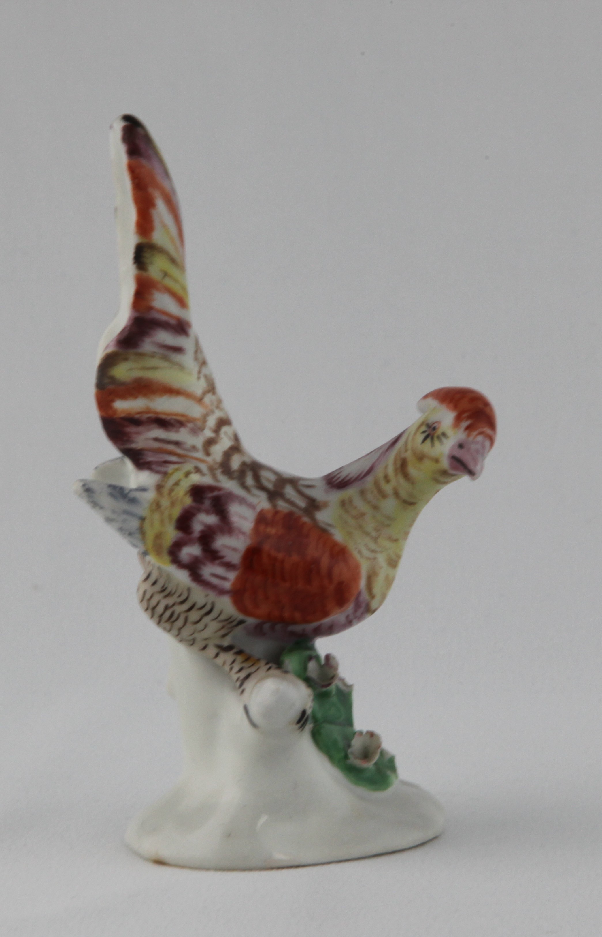 One of an extremely rare pair of Plymouth models of pheasants, each modelled with head turned, and tail feathers raised, its plumage decorated in yellow, pale blue, puce, brown and iron red, on tree-stump shaped base, applied with coloured flowers and leaves, circa 1768-70, no marks