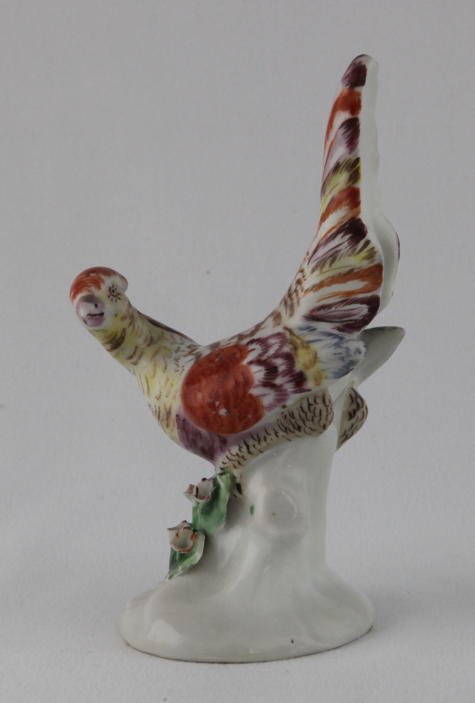 One of an extremely rare pair of Plymouth models of pheasants, each modelled with head turned, and tail feathers raised, its plumage decorated in yellow, pale blue, puce, brown and iron red, on tree-stump shaped base, applied with coloured flowers and leaves, circa 1768-70, no marks