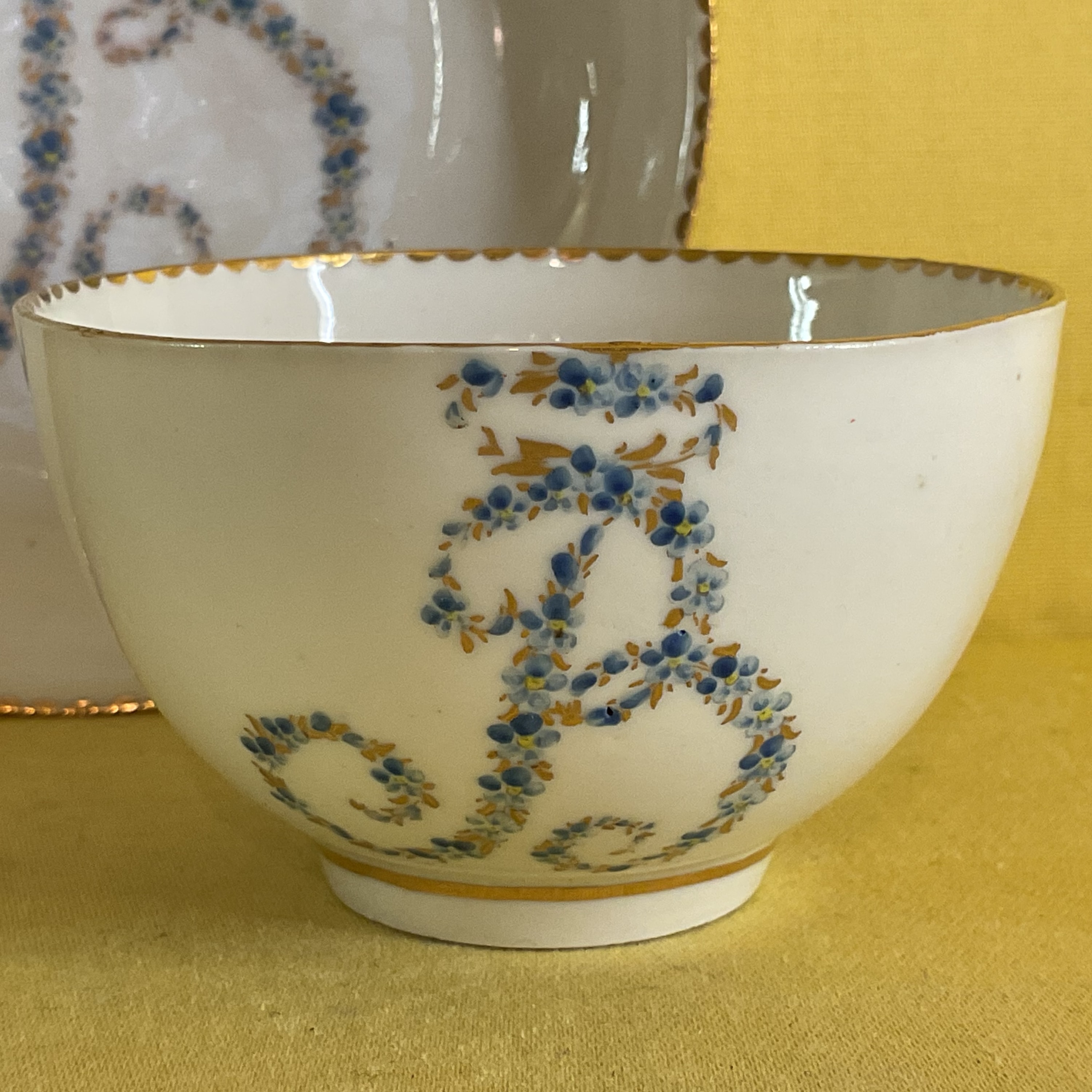 A rare Bristol tea bowl, from the Brice Service, with the large initial 'B' in tiny blue and gilt flowers, within gilt dentil borders, circa 1775, blue painted X marks and the tea bowl with numeral 3 in gilt. Edward Brice was one of Richard Champion's original partners, and this service remained with his family until 1882