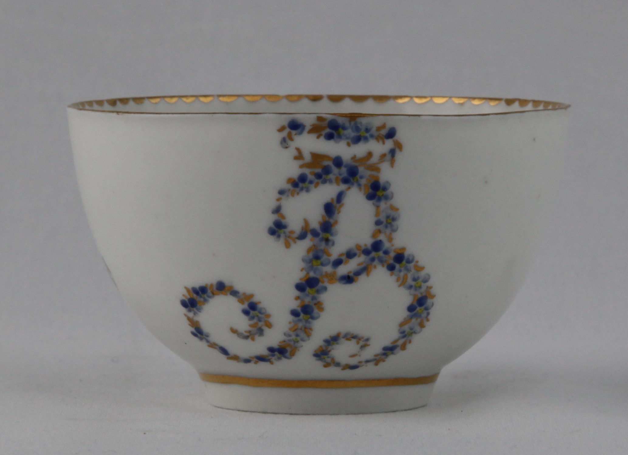 A rare Bristol tea bowl, from the Brice Service, with the large initial 'B' in tiny blue and gilt flowers, within gilt dentil borders, circa 1775, blue painted X marks and the tea bowl with numeral 3 in gilt. Edward Brice was one of Richard Champion's original partners, and this service remained with his family until 1882