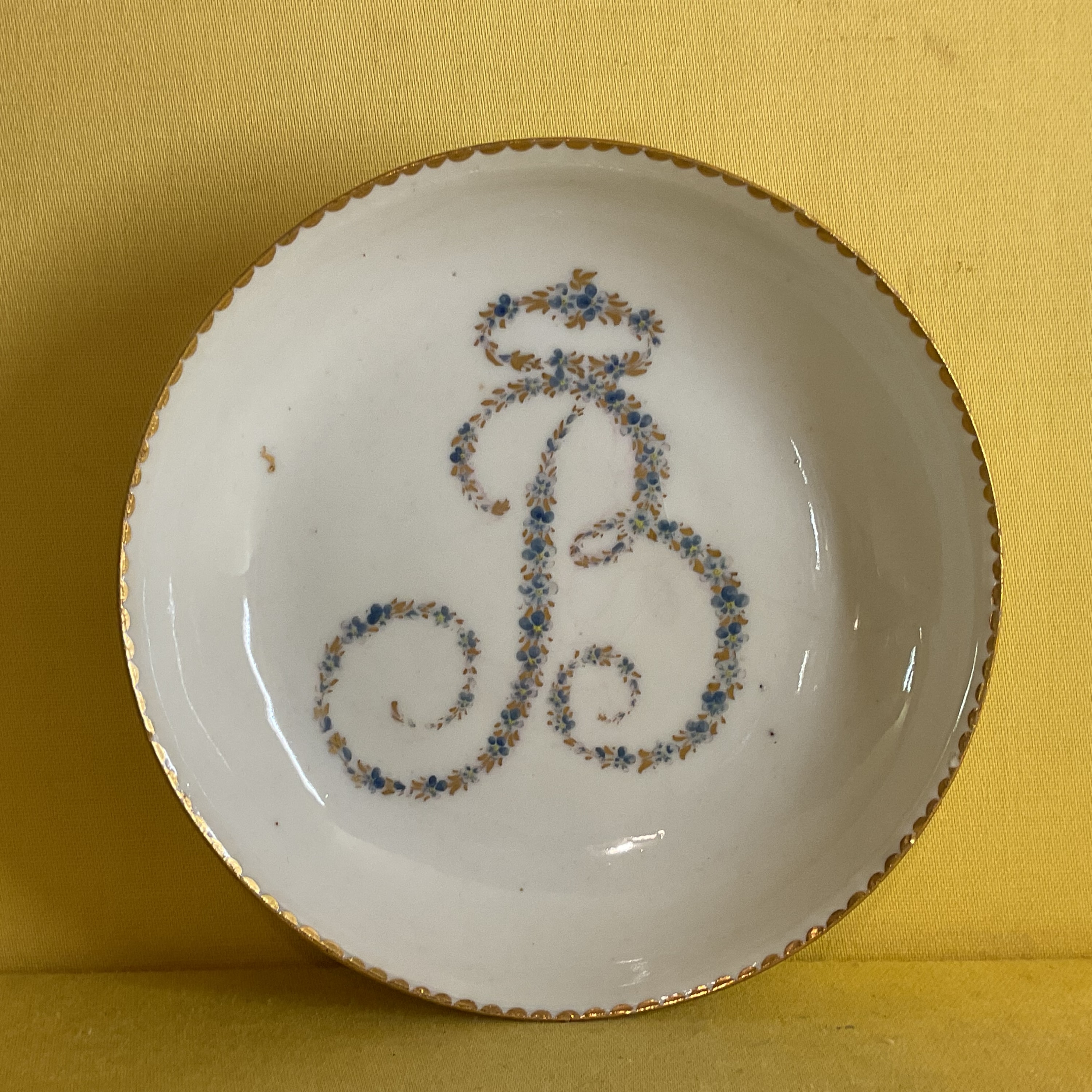 A rare Bristol tea saucer, from the Brice Service, with the large initial 'B' in tiny blue and gilt flowers, within gilt dentil borders, circa 1775, blue painted X marks and the tea bowl with numeral 3 in gilt. Edward Brice was one of Richard Champion's original partners, and this service remained with his family until 1882