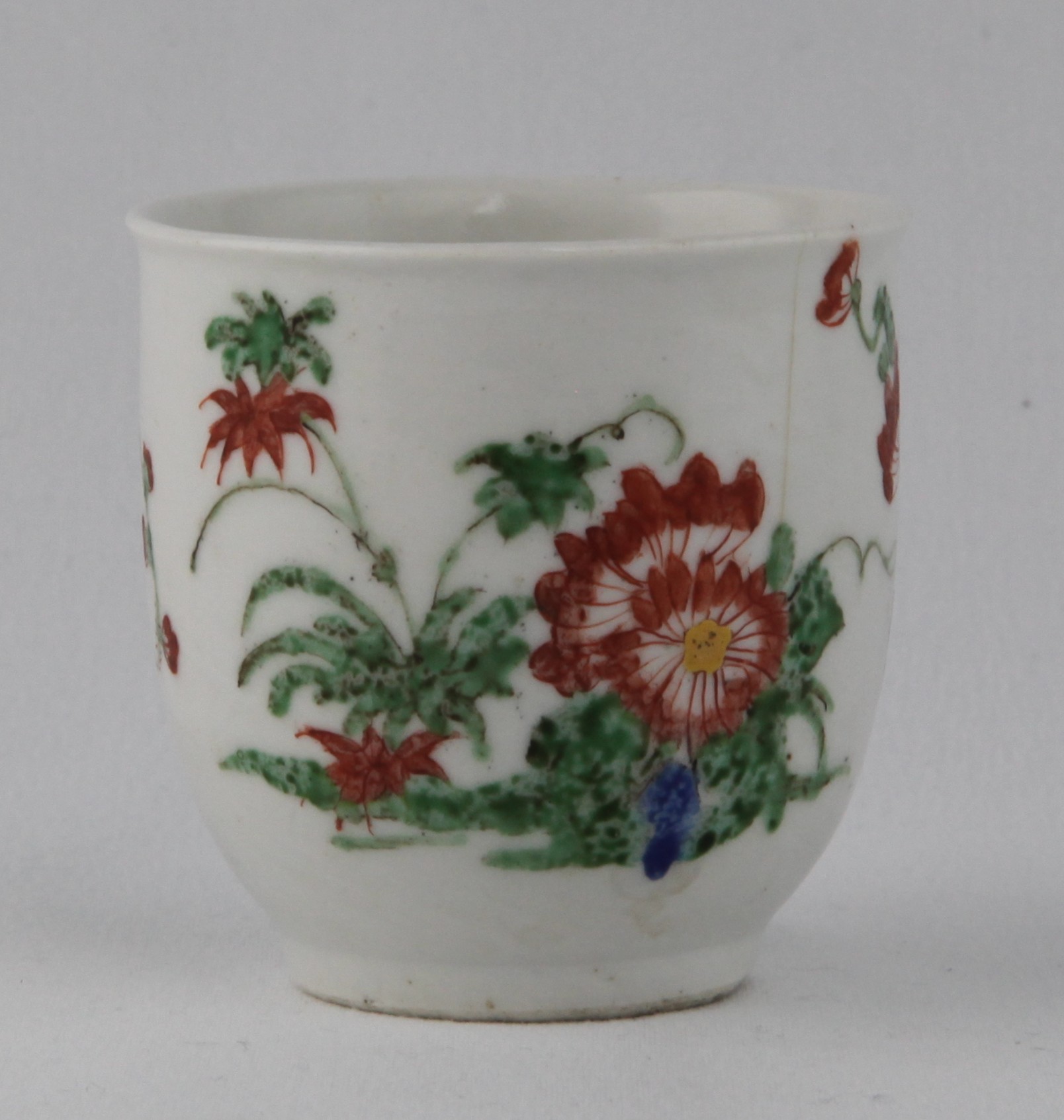 A Plymouth coffee cup, with slightly everted rim and simple loop handle, painted in Chinese famille verte palette with growing flowers and leaves, 2 1/2" high, circa 1770, no mark
