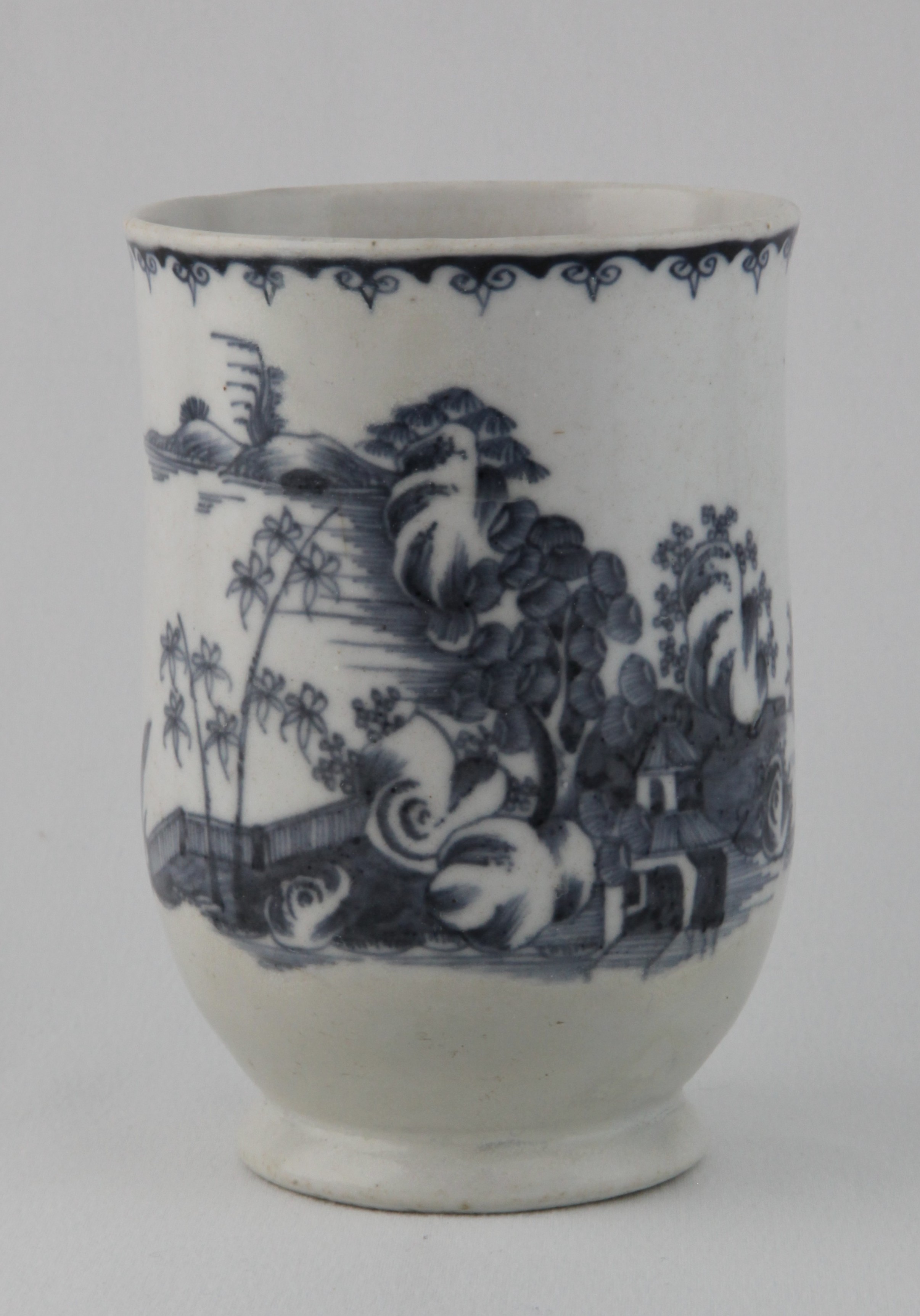 A Plymouth slender baluster shaped mug, with notched loop handle, painted in underglaze blue in Chinese style with a central pavilion, in an extensive river landscape with a fence, bamboo and rockwork, beneath a stylised ruyi head band, 5" high, circa 1770, blue painted tin mark