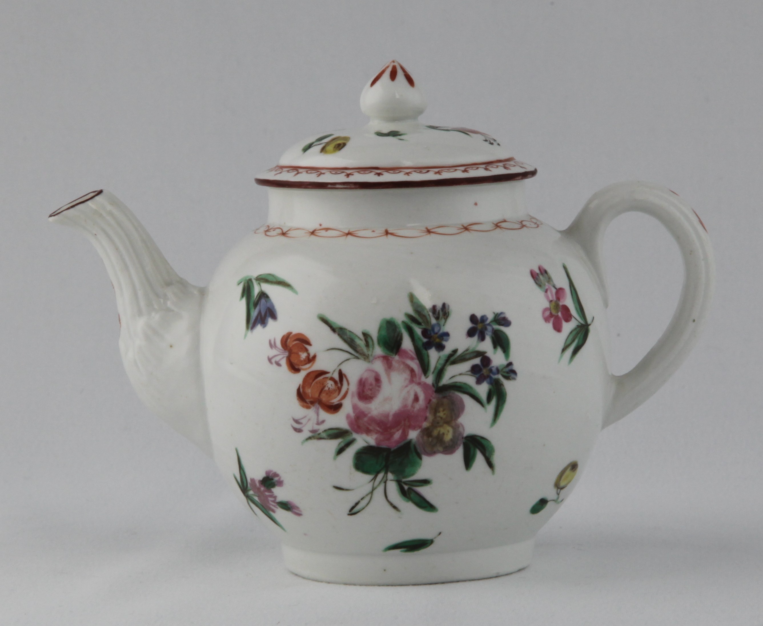 A Bristol small globular teapot and cover, with loop handle, fluted and leaf moulded spout and pointed knop, painted in coloured enamels with sprays of flowers and leaves, and scattered flowers, within iron red interlinked chain borders, 4 1/2" high, circa 1770, no mark