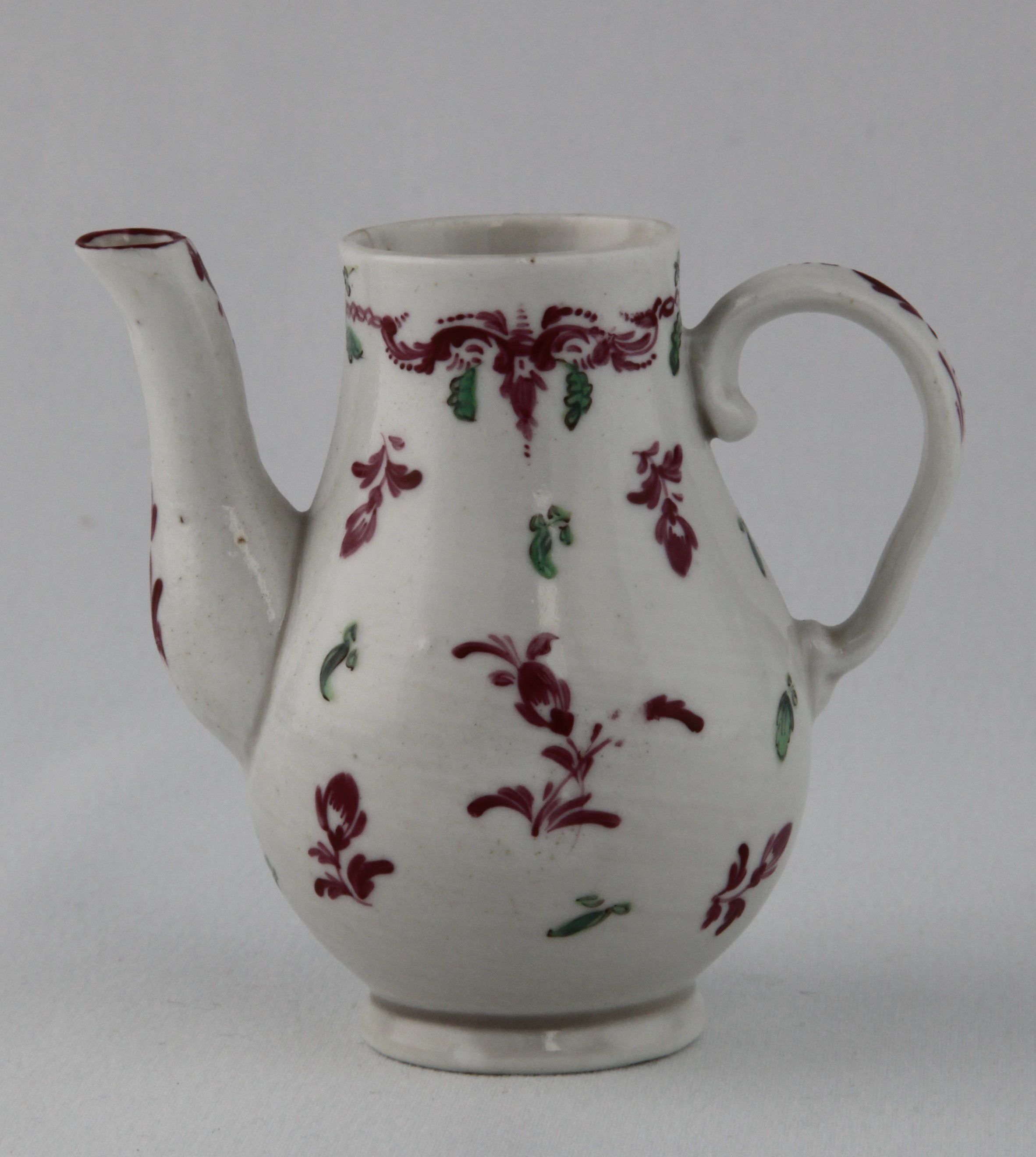 An extremely rare Bristol miniature baluster shaped coffee pot, with ear shaped handle, painted in puce and green with scattered flowers and leaves, beneath a puce scroll band, with green pendant leaves, 3 1/4" high, circa 1772, blue crossed swords mark painted over in brown