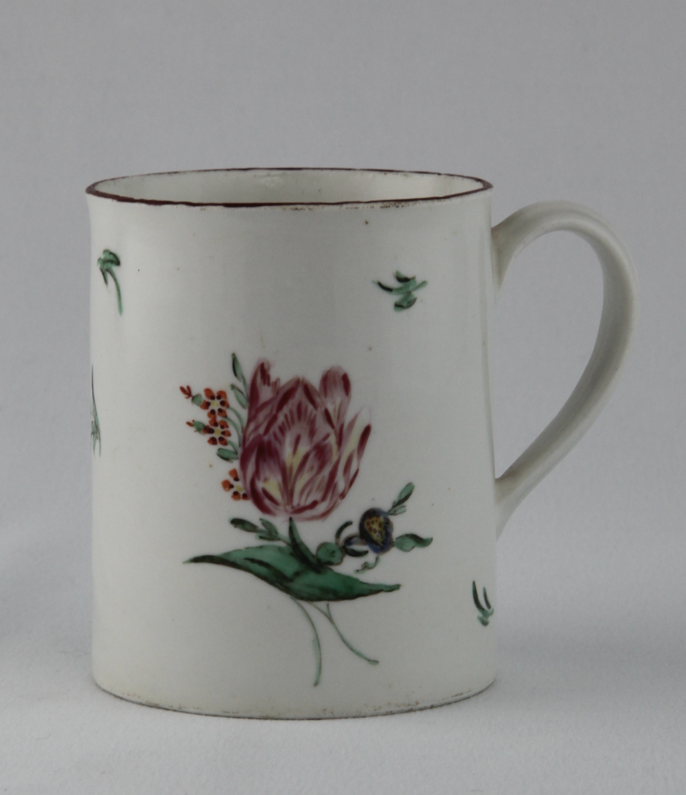 A Bristol small cylindrical mug, with notched loop handle, unusually painted in coloured enamels with a flower spray and scattered flowers, brown line rim, 3 3/8" high, circa 1775, blue painted X mark and numeral 17