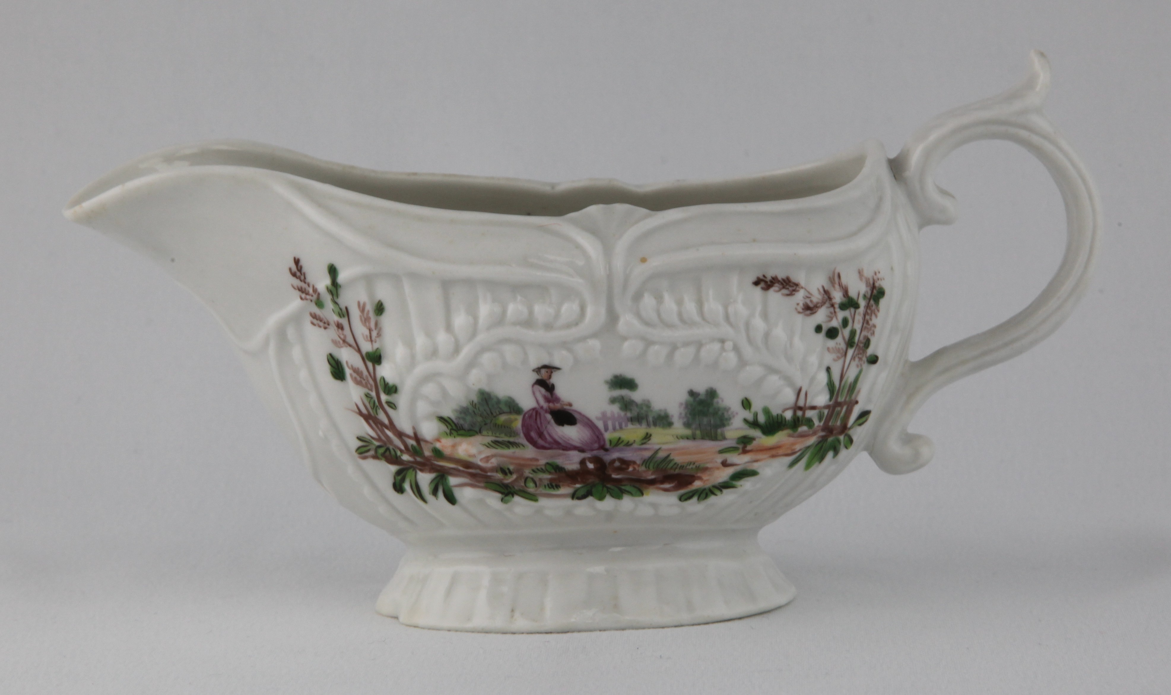 A Plymouth oval sauceboat, with 'S' scroll handle, with leaf moulded thumb piece, unusually painted in coloured enamels with elegant figures in European landscapes, within leaf moulded cartouches, on a fluted ground, 7 1/4" long, circa 1770, no mark