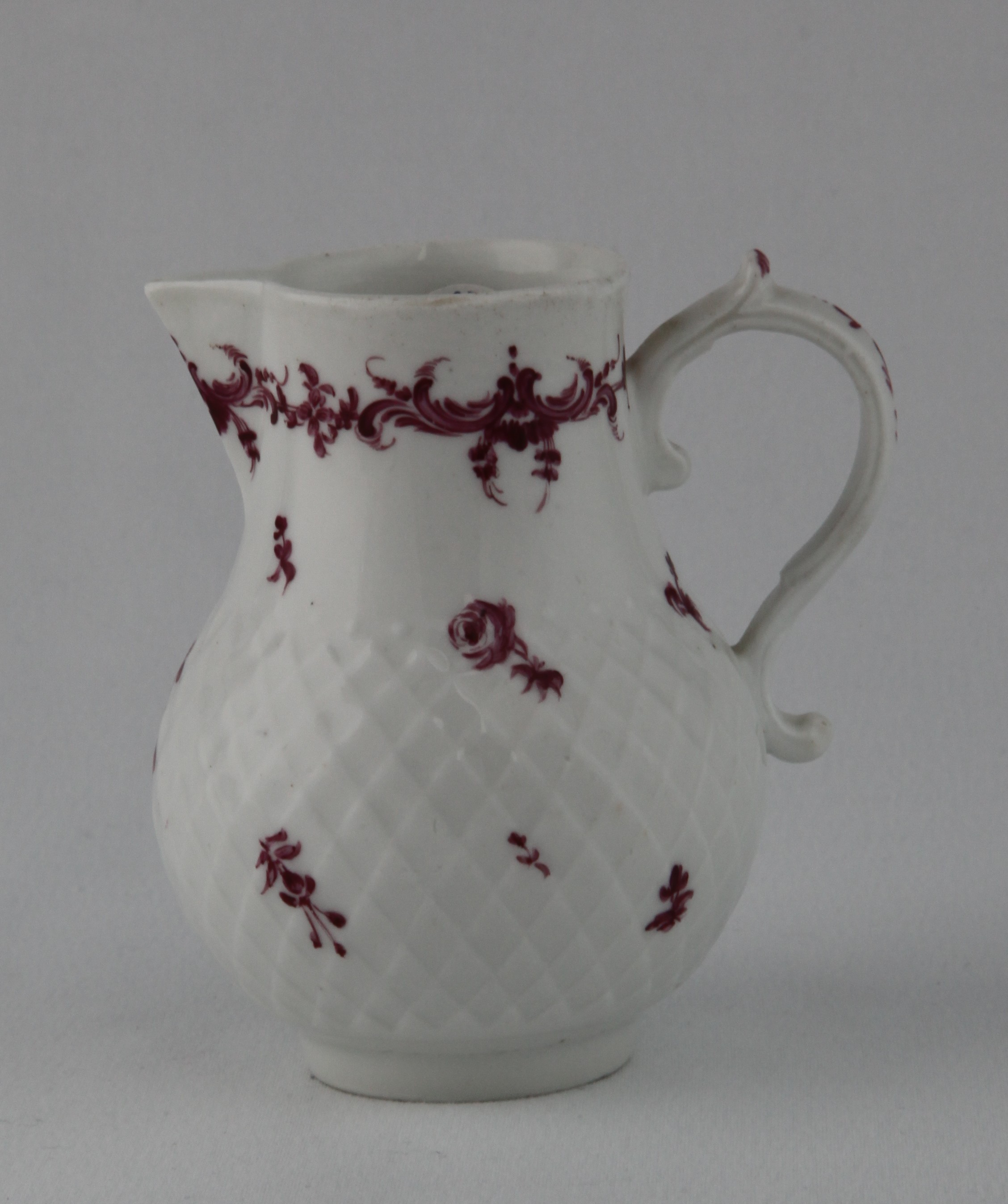A rare Bristol baluster shaped sparrow beak milk jug, the 'S' scroll handle with leaf moulded thumb piece, painted in purple monochrome with scattered flowers, on a pinecone moulded ground, beneath a flower and scroll band, 3 3/4" high, circa 1775, no mark