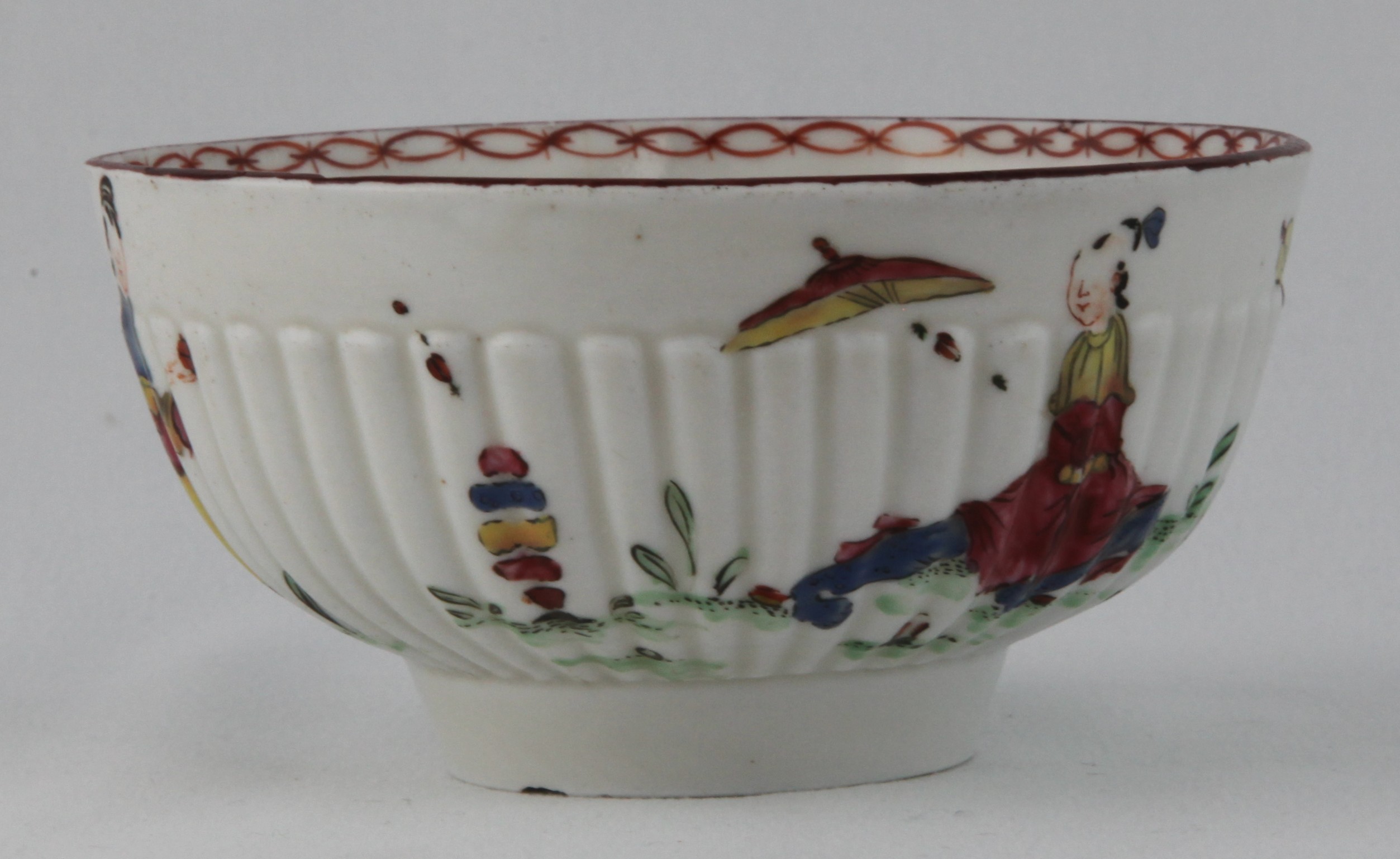 A rare Bristol small part fluted round bowl,  painted in Chinese famille rose style with three figures in a garden, beneath a brown line rim, the interior with an iron red interlinked band, 4 1/4" diameter, circa 1772, blue painted crossed swords mark and blue X