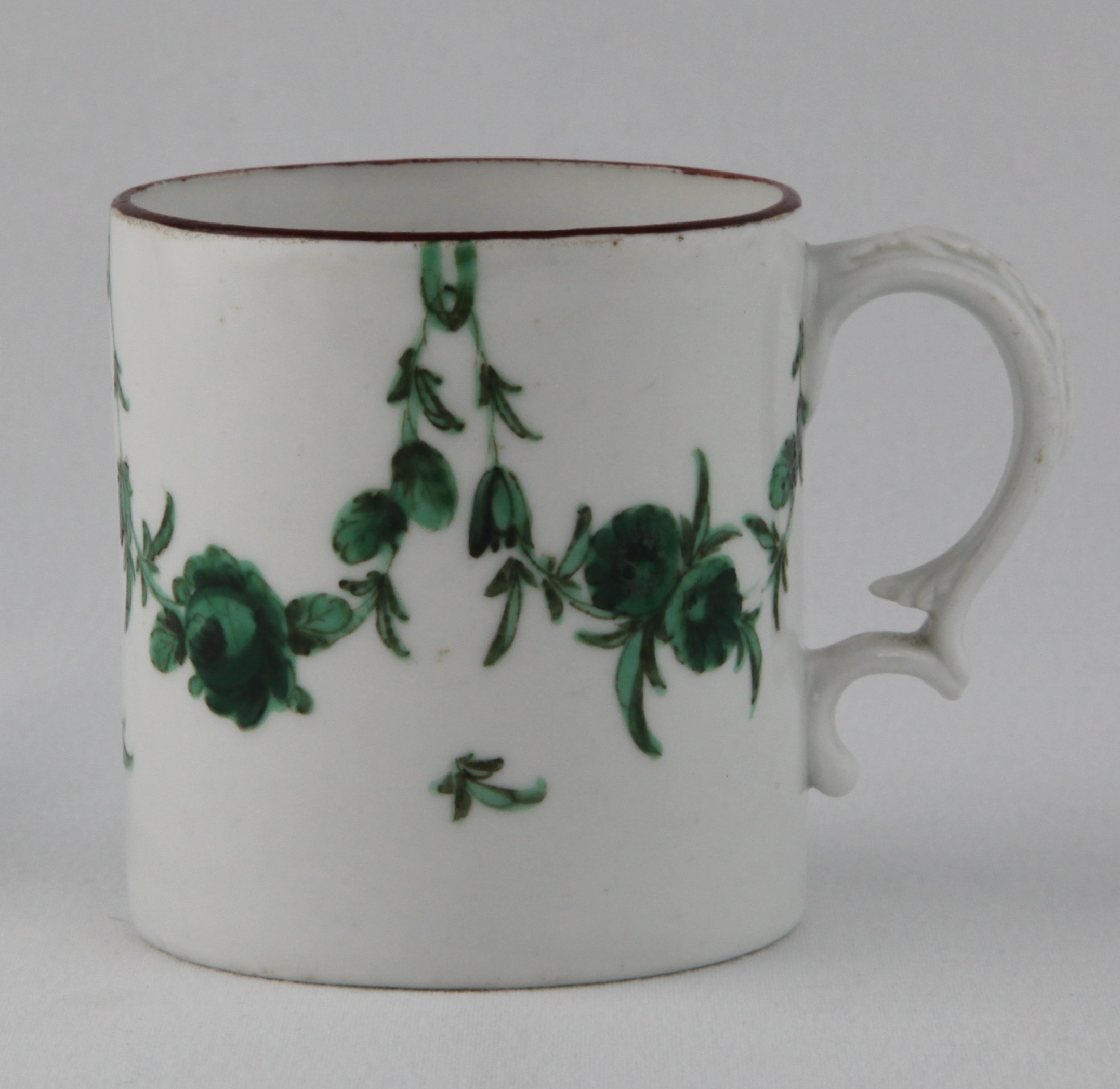 A Bristol small cylindrical mug or can, with harebell moulded ear shaped handle, painted in green monochrome with swags of flowers and leaves, suspended from green loops, brown line rim, 2 3/4" high, circa 1775, no mark