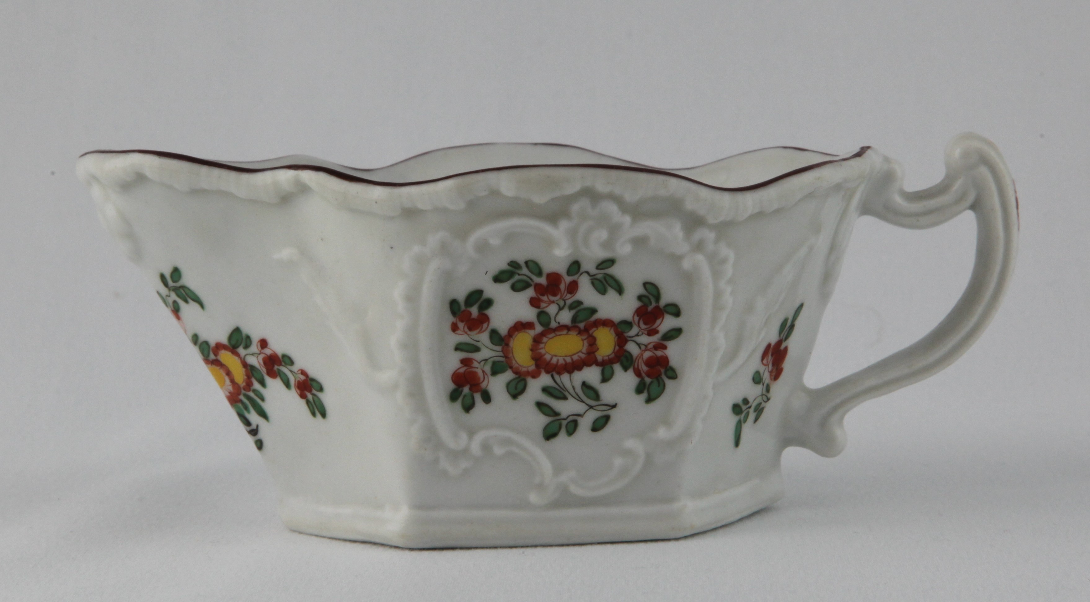 A Plymouth hexagonal sauce boat, the angular scroll handle with shell moulded upper terminal, painted in Japanese Kakiemon palette with flowers and leaves, within 'C' scroll moulded cartouches, the 'melting ice' border with a brown band, 5 3/4" long, circa 1770, no mark