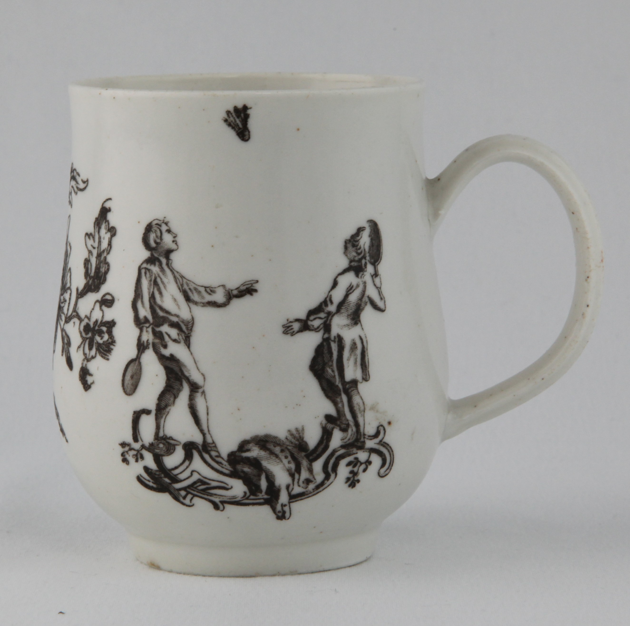 A rare Bristol baluster shaped mug, with notched loop handle, printed in black after Hubert Gravelot with 'Blind Man's Buff' and 'Battledore and Shuttlecock', flanking a spray of flowers and leaves, 3 3/4" high, circa 1772-75, no mark.