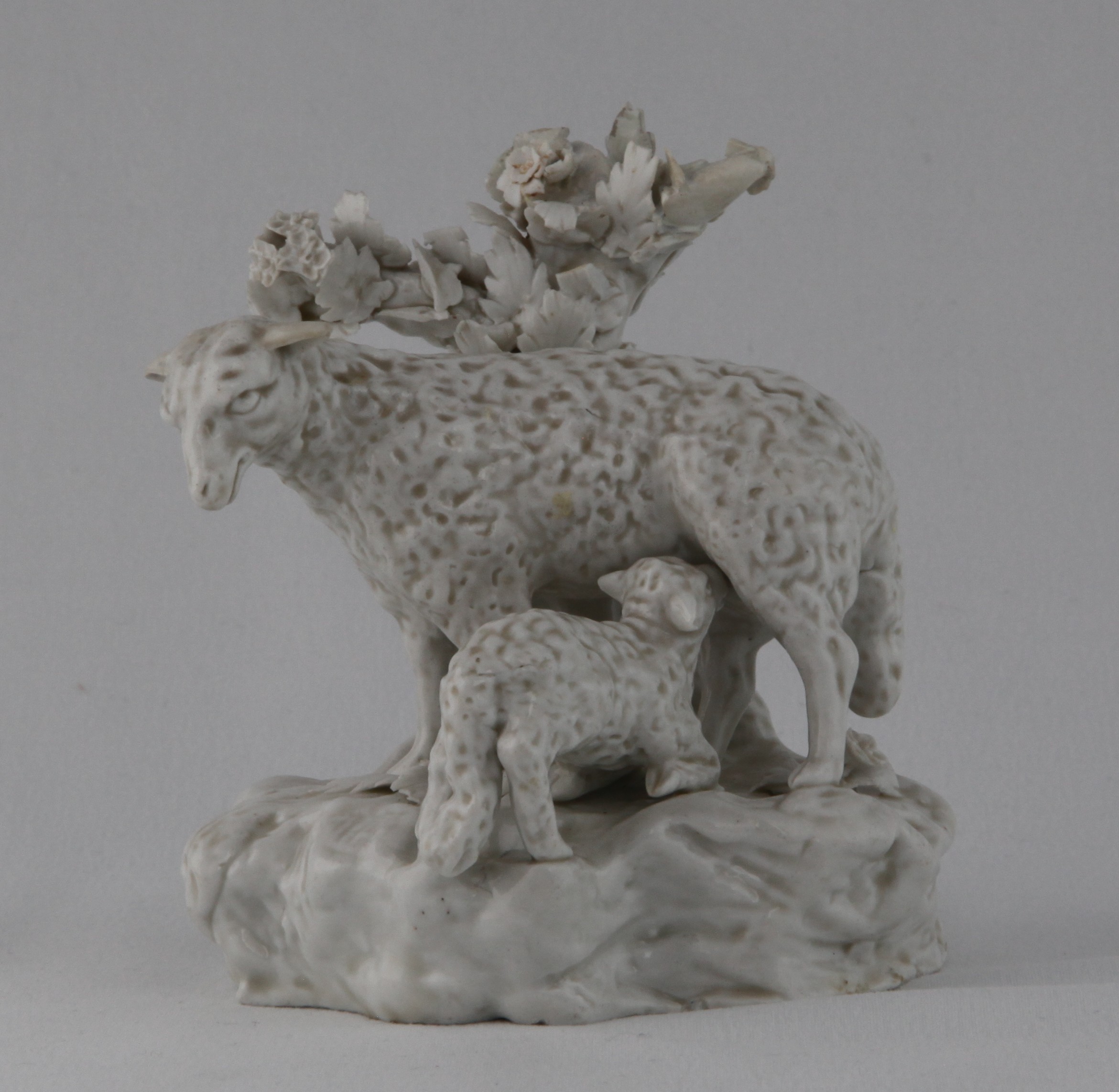 A Plymouth group of a ewe suckling a lamb, in the white, before a leaf applied tree-stump, on rocky mound base, 4 1/4" high, circa 1770