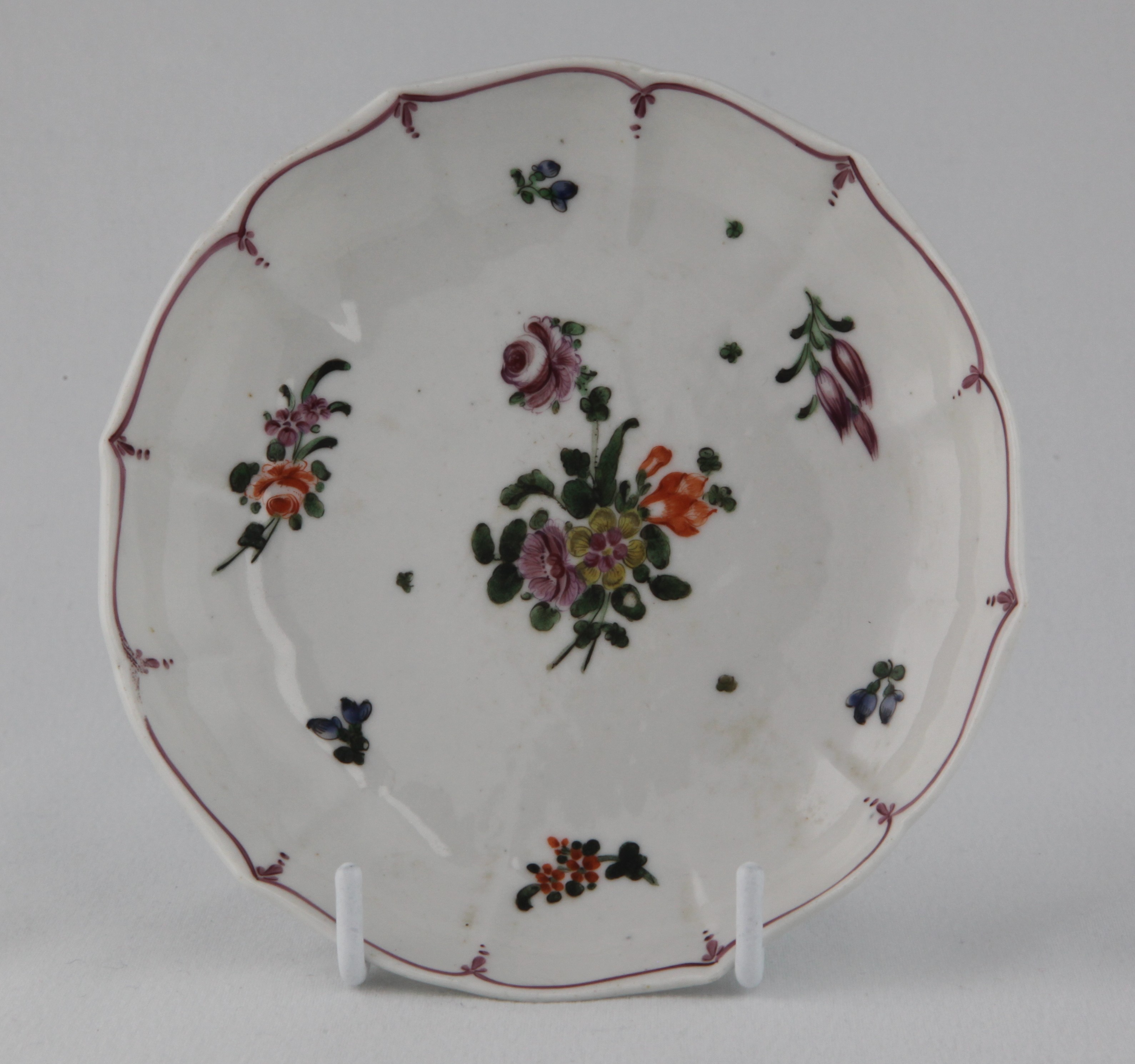 A rare Bristol saucer, of simple fluted form, painted in coloured enamels with sprays of flowers and leaves, and scattered flowers, within puce line and pendant borders, circa 1775, no marks