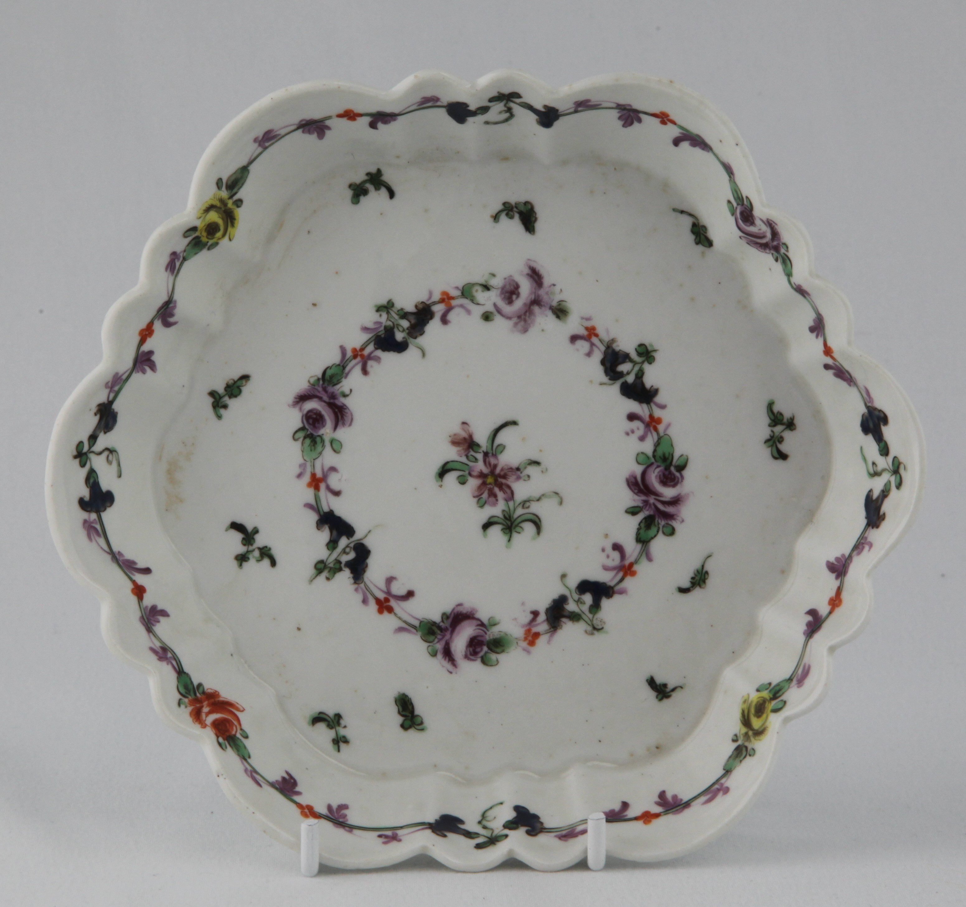 A rare Bristol hexagonal large teapot stand, painted in coloured enamels with a simple flower spray, and with scattered flowers and leaves, the fluted border with a further band of flowers and leaves, 6 1/2" wide, circa 1775, no mark