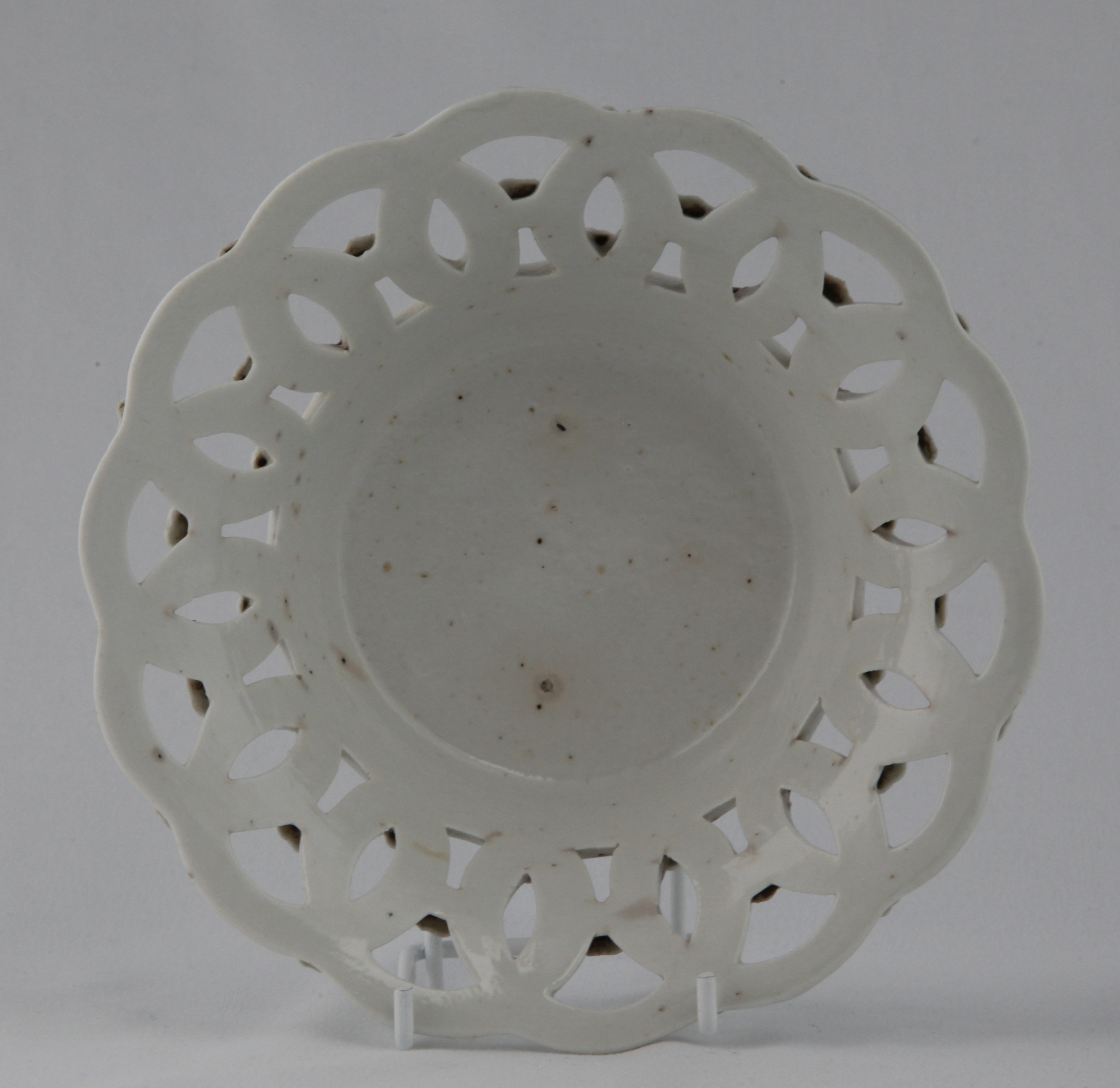 One of a rare pair of Bristol shallow round baskets, after Worcester originals, in the white, each pierced with interlinked roundels, the exterior applied with flower heads, 6 3/4" diameter, circa 1772, no mark