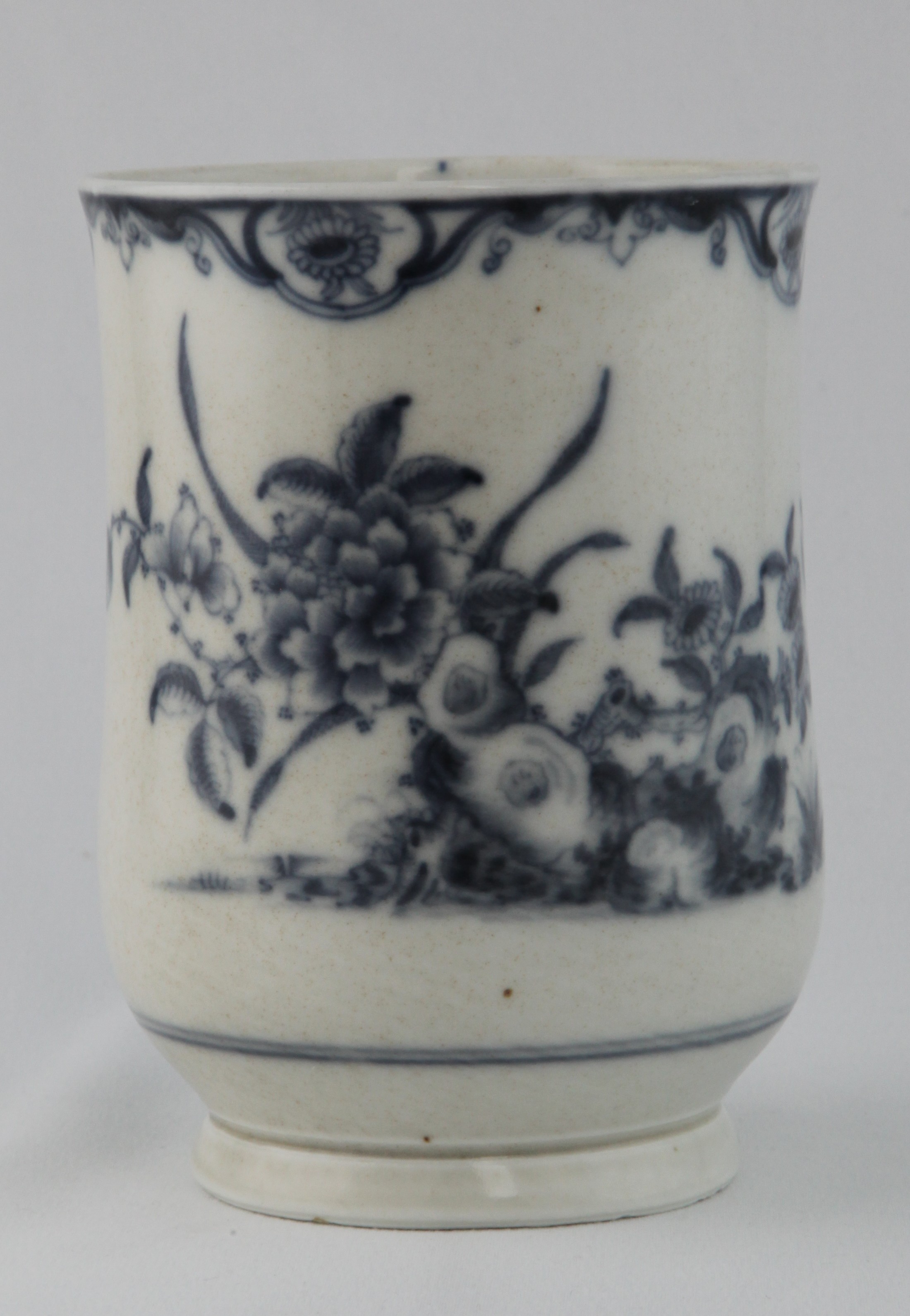 A Plymouth baluster shaped large mug, with notched loop handle, painted in underglaze blue in Chinese style with flowers issuing from rockwork, and with flying insect, beneath a flower panelled scroll band, 5 1/2" high, circa 1770, blue painted tin mark