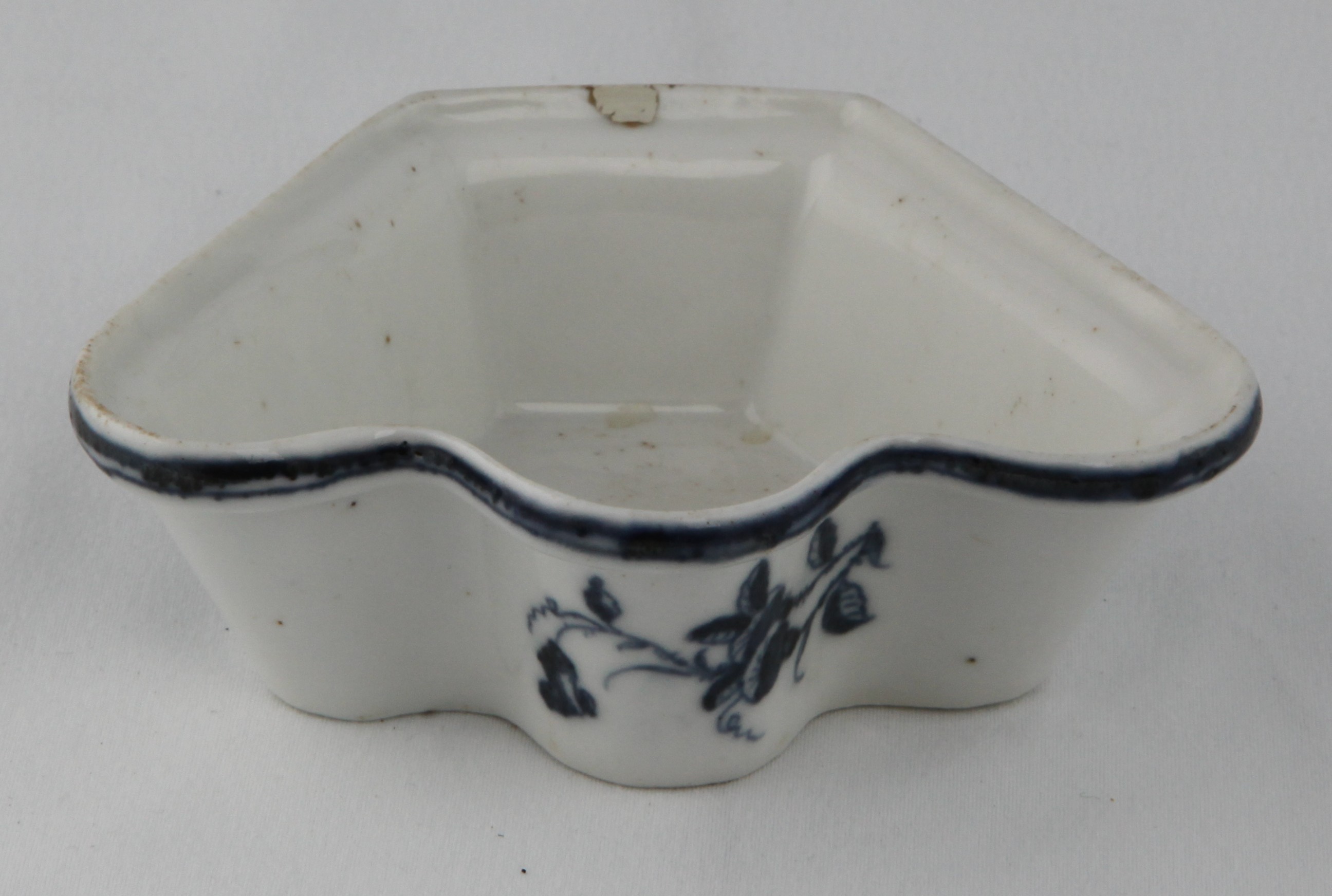 A Plymouth fan shaped dish, from an hors d'oeuvre set, the exterior painted in underglaze blue with simple flower sprays, beneath a narrow diaper band, 4 3/4" wide, circa 1770