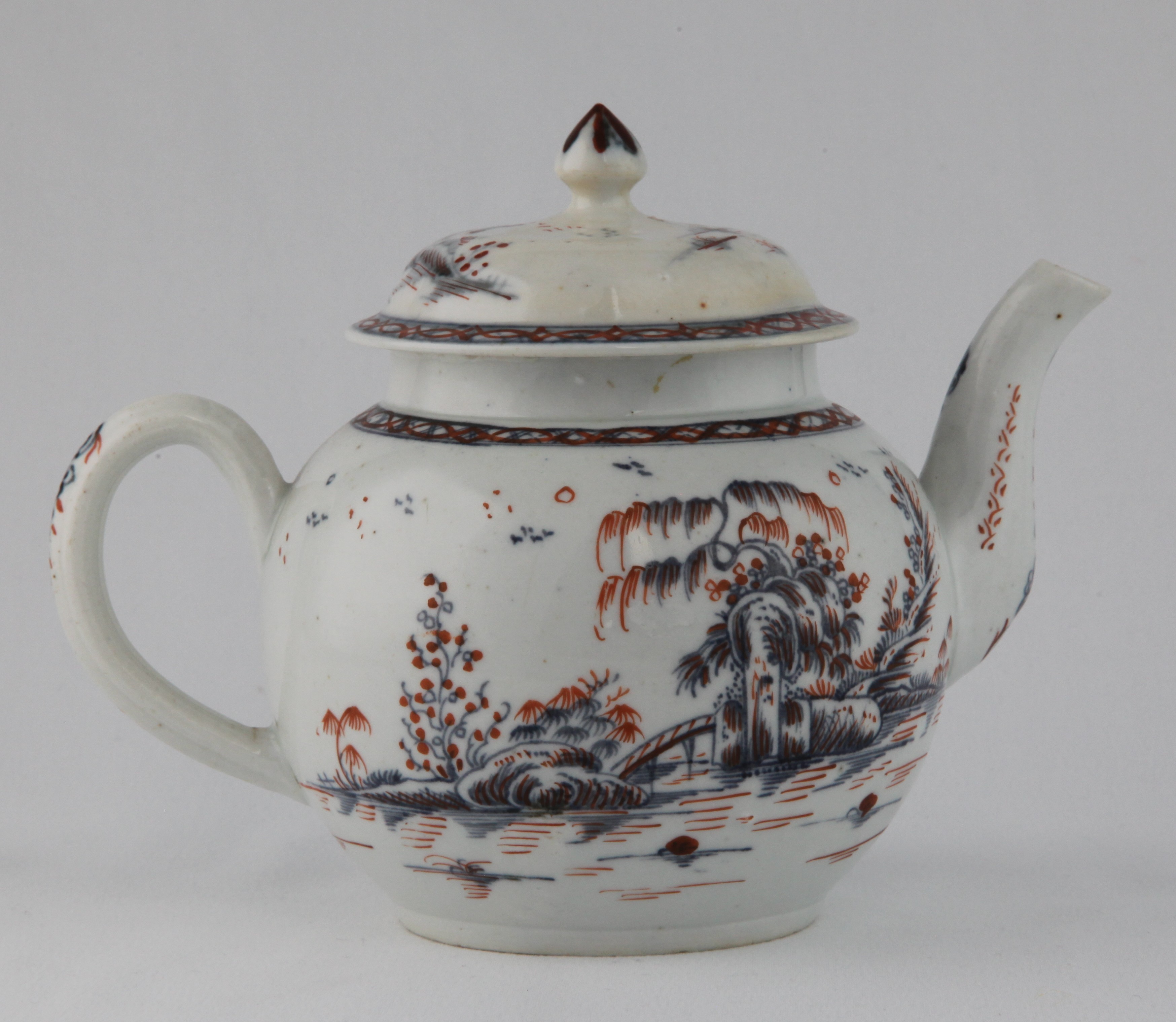 A Plymouth globular teapot and cover, with loop handle and pointed knop, painted in underglaze blue in Chinese style with a bridge in a rocky river landscape, within diaper borders, and picked out in iron red, 5 1/2" high, circa 1770, no mark