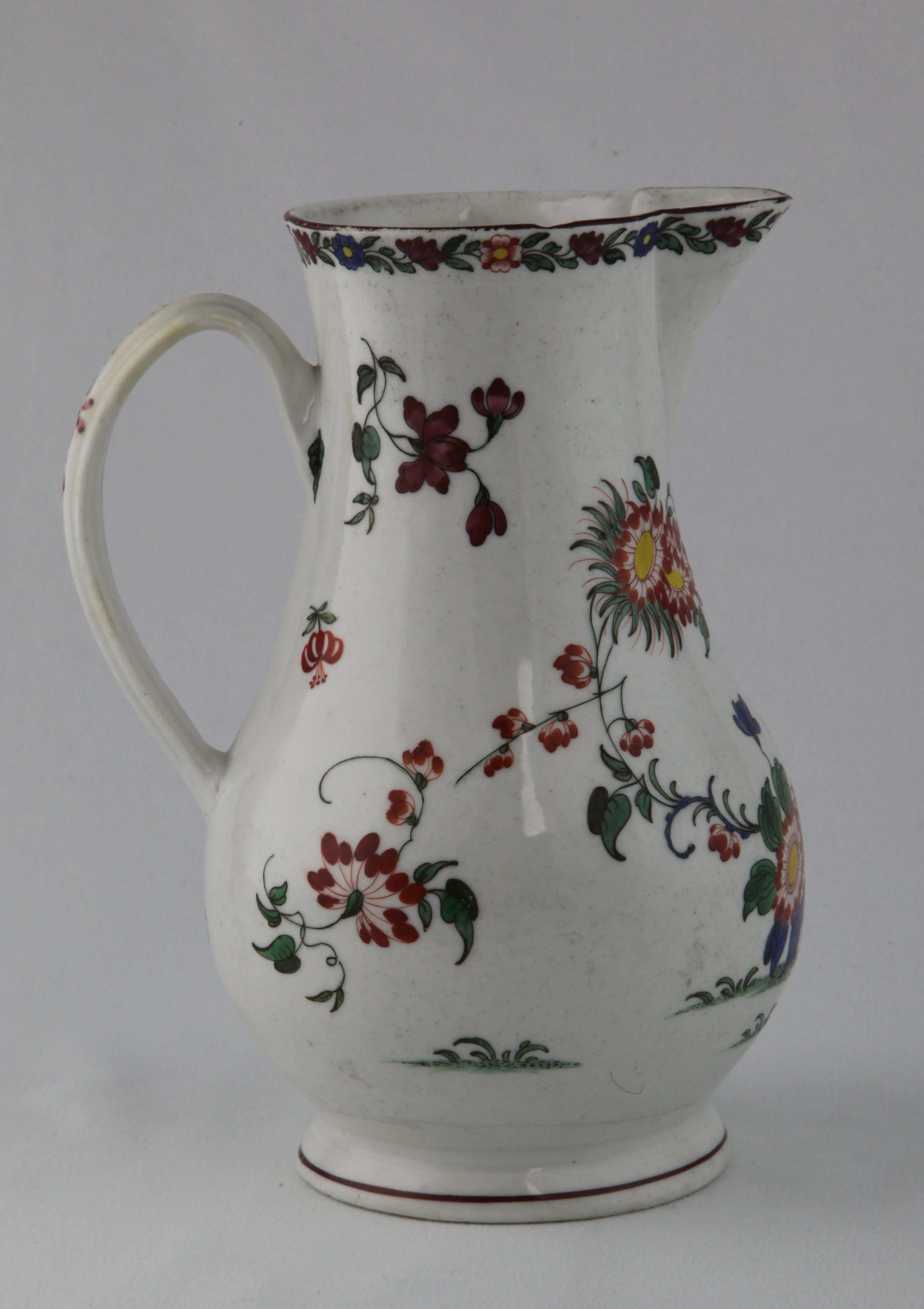 A Plymouth large baluster shaped jug, with notched loop handle, painted in Japanese Kakiemon palette with growing flowers and leaves, flanked by flower sprays, beneath a flower and leaf scroll band, brown line rim, 7 1/2" high, circa 1770, painted tin mark