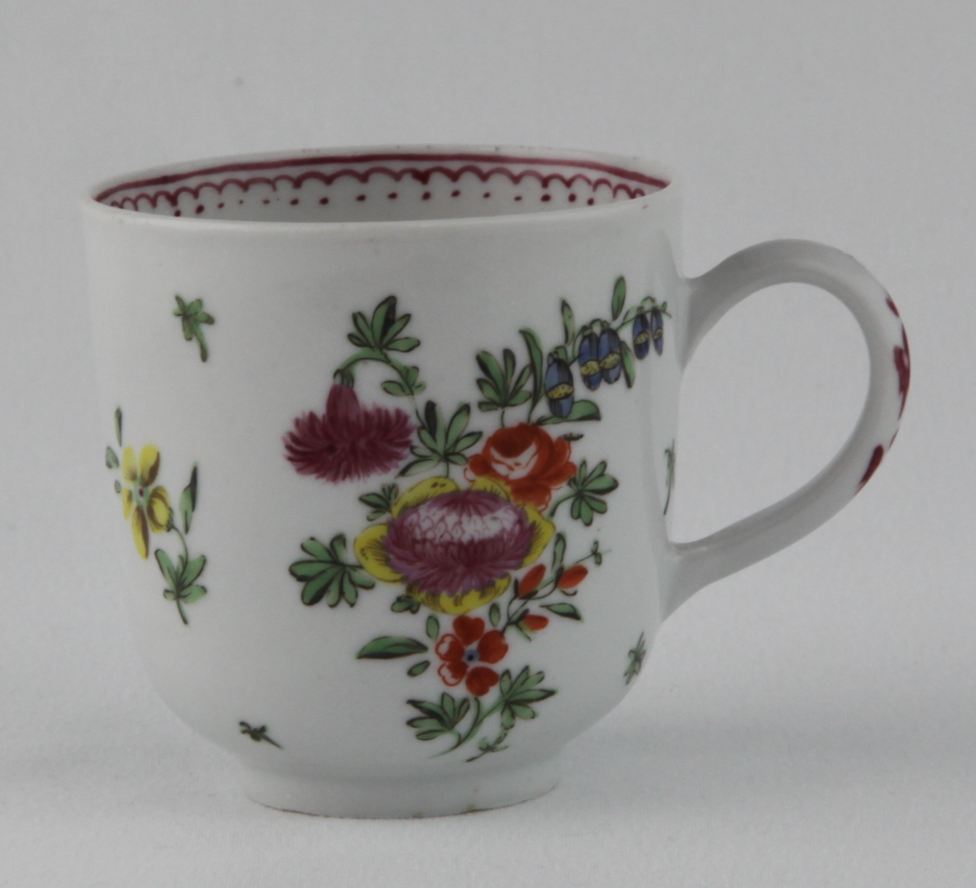 A Bristol coffee cup, with loop handle, painted in coloured enamels with a spray of flowers and leaves and scattered flowers, the interior rim with an iron red loop and dot band, 2 1/2" high, circa 1775, no mark