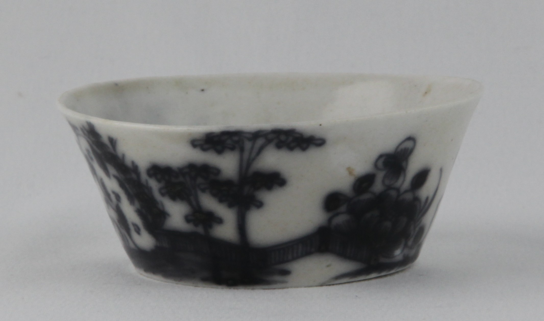 A rare Plymouth small flared round patty pan, the exterior painted in underglaze blue in Chinese style with bamboo and peony in a fenced river landscape, the interior with the shadowy traces of similar decoration, 3 3/4" diameter, circa 1770, blue painted tin mark