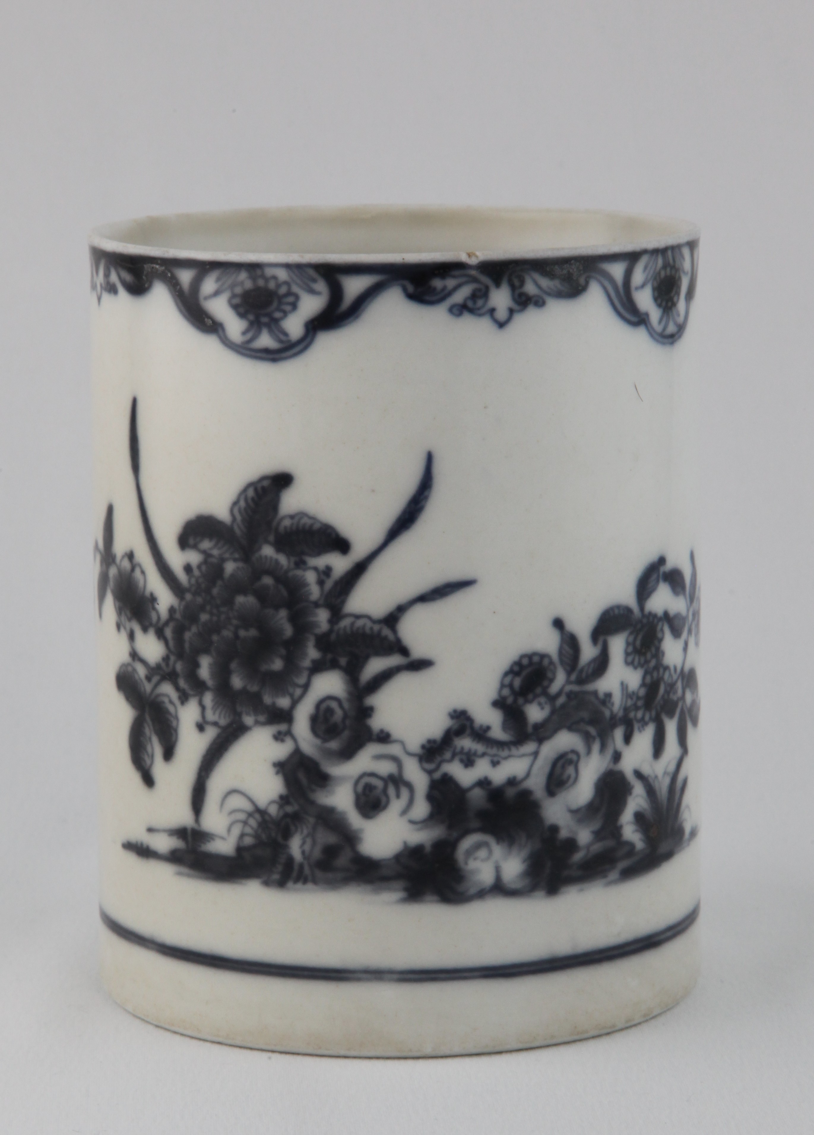 A Plymouth cylindrical mug, with notched loop handle, painted in underglaze blue in Chinese style with flowers issuing from rockwork, and a winged insect, beneath a flower panelled scroll band, the handle terminals flanked by painted leaf scrolls, 5 1/4" high, circa 1770, blue painted tin mark