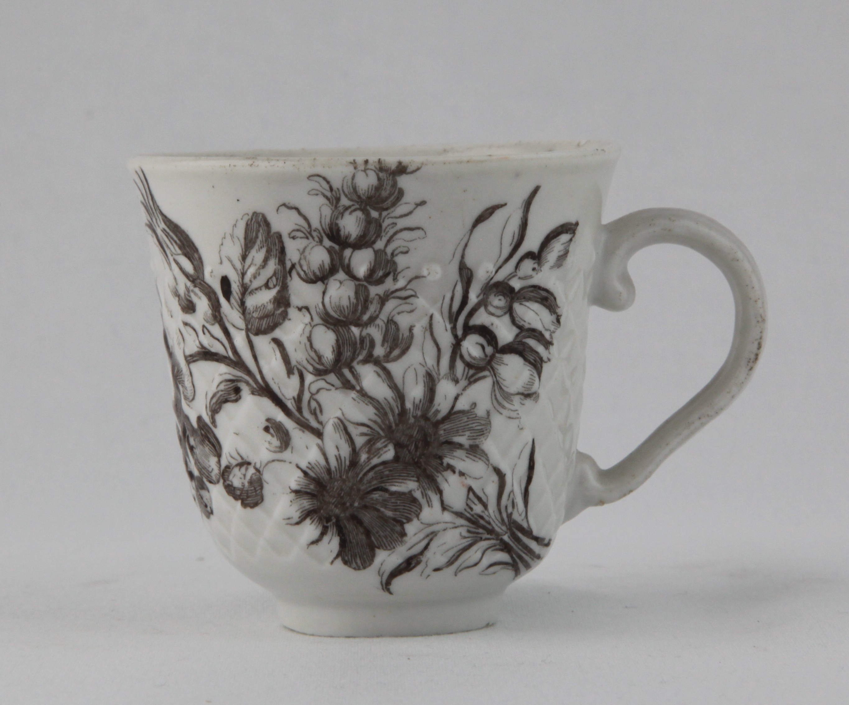 A rare Bristol coffee cup, with ear shaped handle,  pinecone moulded and finely printed in black with a flower spray, and the cup printed with a butterfly, circa 1775, no mark