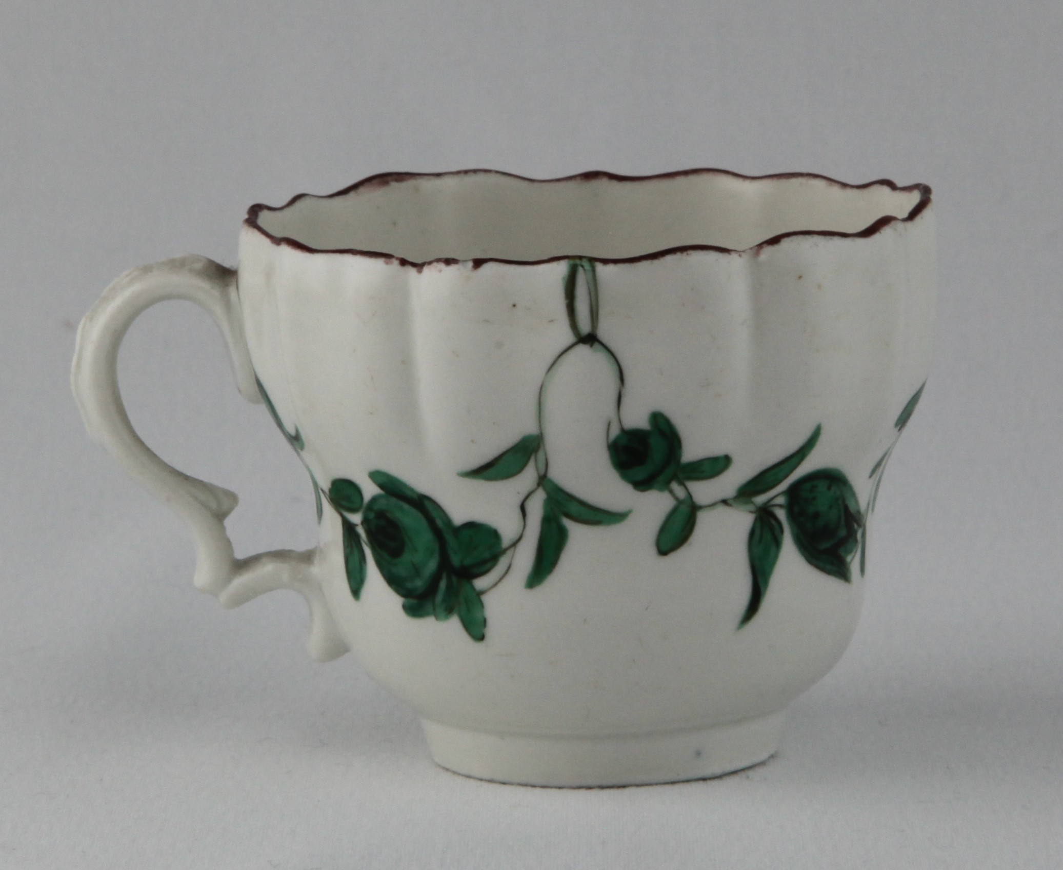 A Bristol ogee shaped coffee cup with laurel moulded ear shaped handle, painted in green and black with floral garlands, suspended from rings, within brown line borders, circa 1775, blue painted B1 mark